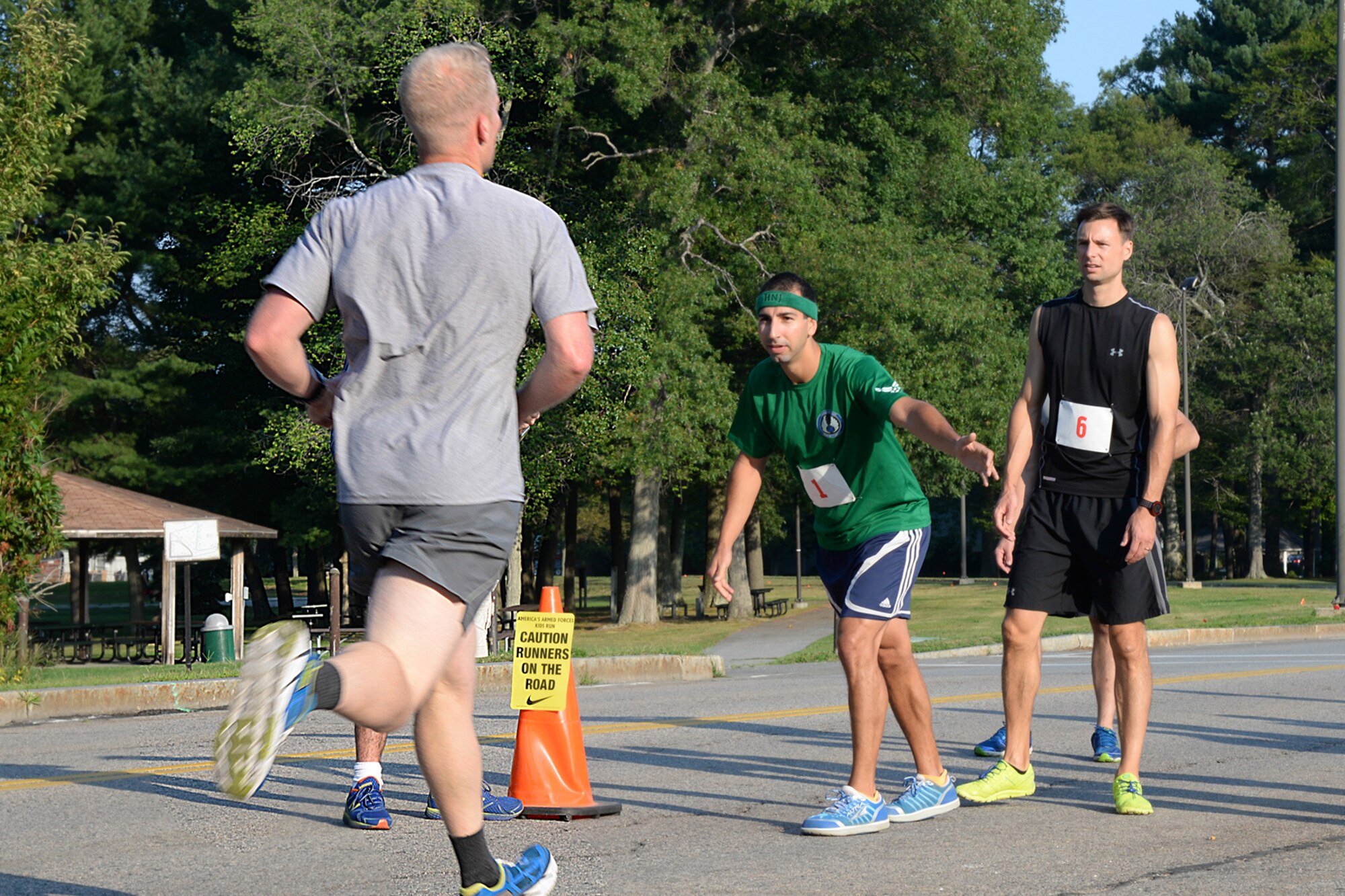 First Lt. William Cowan prepares to hand off a baton to Capt. David Rothzeid during the August Dog Days 3 x 1 mile relay race outside the Fitness and Sports Center Aug. 19, while Adam Norige watches. A total of nine teams and 25 participants participated in the annual event. (U.S. Air Force photo by Linda LaBonte Britt)