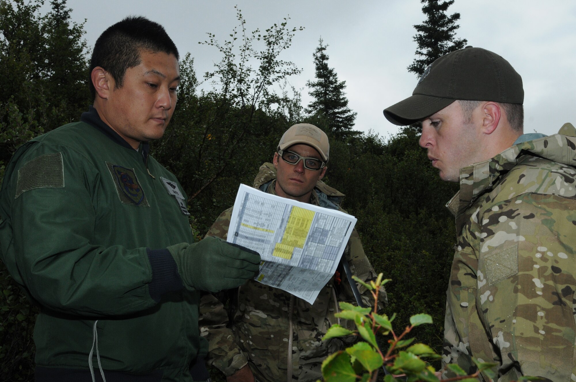 Japan Air Self-Defense Force Maj. Tomohiro Saito, a pilot with the Air Rescue Wing, discusses rescue equipment with U.S. Air Force survival, evasion, resistance and escape specialists Staff Sgt. Tyler Boyer with the Alaska Air National Guard's 212th Rescue Squadron, and Staff Sgt. Levi Wood with the 353rd Combat Training Squadron at Eielson Air Foce Base, Alaska, during an immediate shoot-down exercise Aug. 12, 2015, at Eielson AFB as part of RED FLAG-Alaska (RF-A) 15-3.  RF-A is a Pacific Air Forces commander-directed field training exercise for U.S. and partner nation forces, providing combined offensive counter-air, interdiction, close air support and large force employment training in a simulated combat environment.  (U.S. Air Force photo by Master Sgt. Ralph Kapustka/Released)