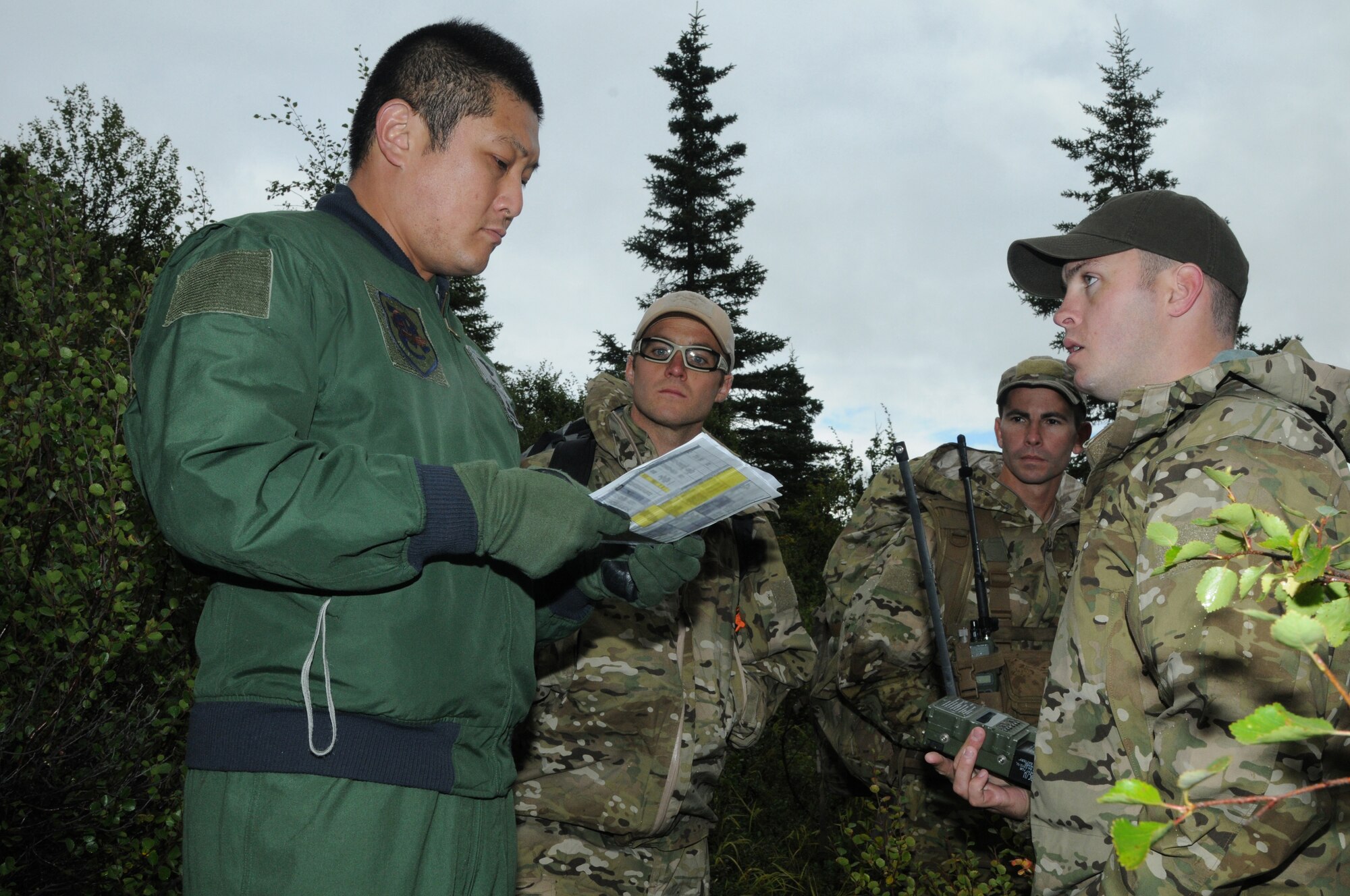 Japan Air Self-Defense Force Maj. Tomohiro Saito, a pilot with the Air Rescue Wing, listens as U.S. Air Force survival, evasion, resistance and escape specialists Staff Sgt. Tyler Boyer and Airman 1st Class Matt O'Brien, both with the Alaska Air National Guard's 212th Rescue Squadron, and Staff Sgt. Levi Wood with the 353rd Combat Training Squadron at Eielson Air Foce Base, Alaska, discuss pilot rescue equipment during an immediate shoot-down exercise Aug. 12, 2015, at Eielson AFB as part of RED FLAG-Alaska (RF-A) 15-3.  RF-A is a Pacific Air Forces commander-directed field training exercise for U.S. and partner nation forces, providing combined offensive counter-air, interdiction, close air support and large force employment training in a simulated combat environment.  (U.S. Air Force photo by Master Sgt. Ralph Kapustka/Released)