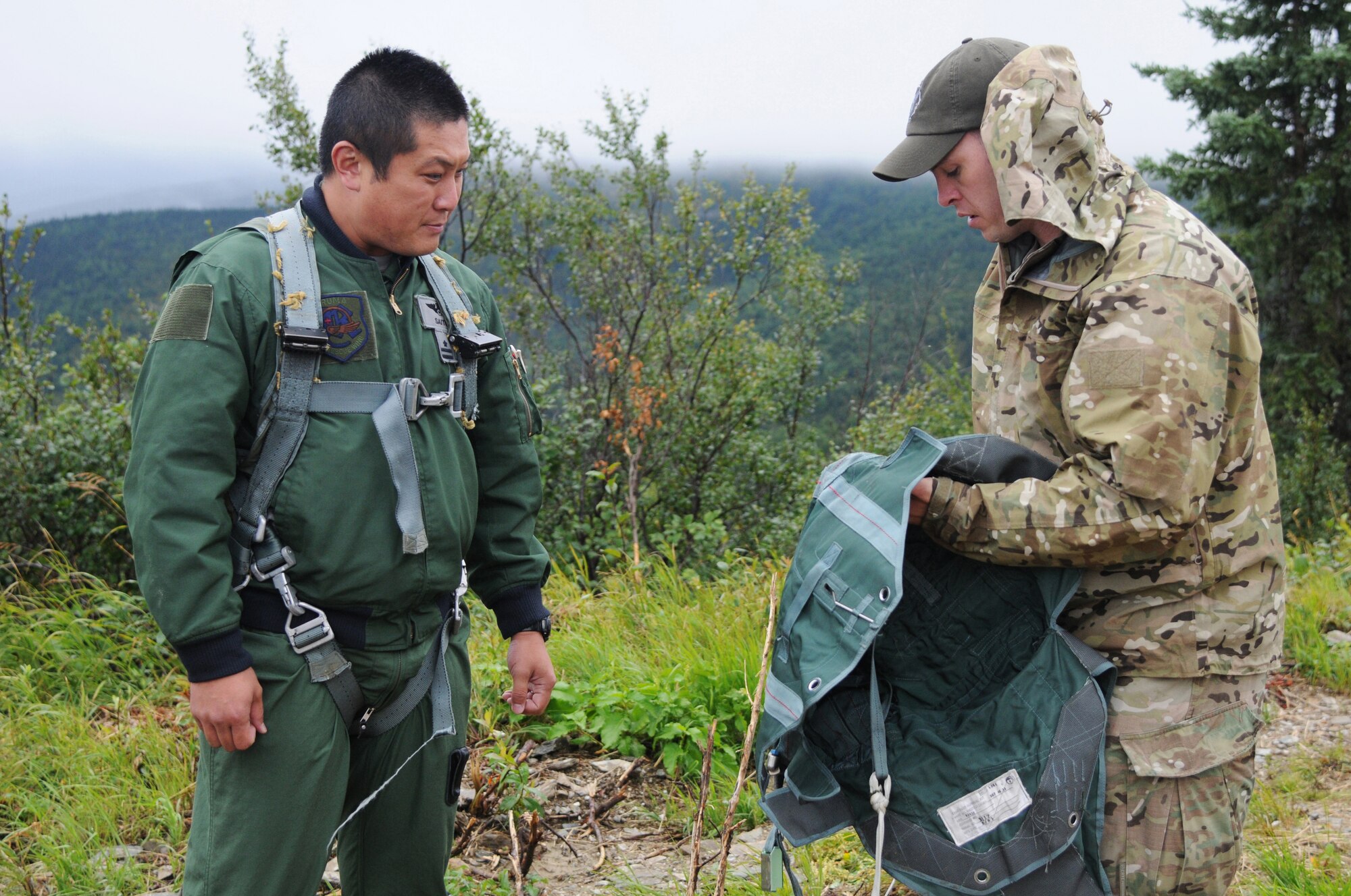 Japan Air Self-Defense Force Maj. Tomohiro Saito, a pilot with the Air Rescue Wing and U.S. Air Force Staff Sgt. Levi Wood, a survival, evasion, resistance and escape specialist with the 353rd Combat Training Squadron, discuss rescue equipment during an immediate shoot-down exercise Aug. 12, 2015, at Eielson Air Force Base, Alaska, as part of RED FLAG-Alaska (RF-A) 15-3.  RF-A is a Pacific Air Forces commander-directed field training exercise for U.S. and partner nation forces, providing combined offensive counter-air, interdiction, close air support and large force employment training in a simulated combat environment.  (U.S. Air Force photo by Master Sgt. Ralph Kapustka/Released)