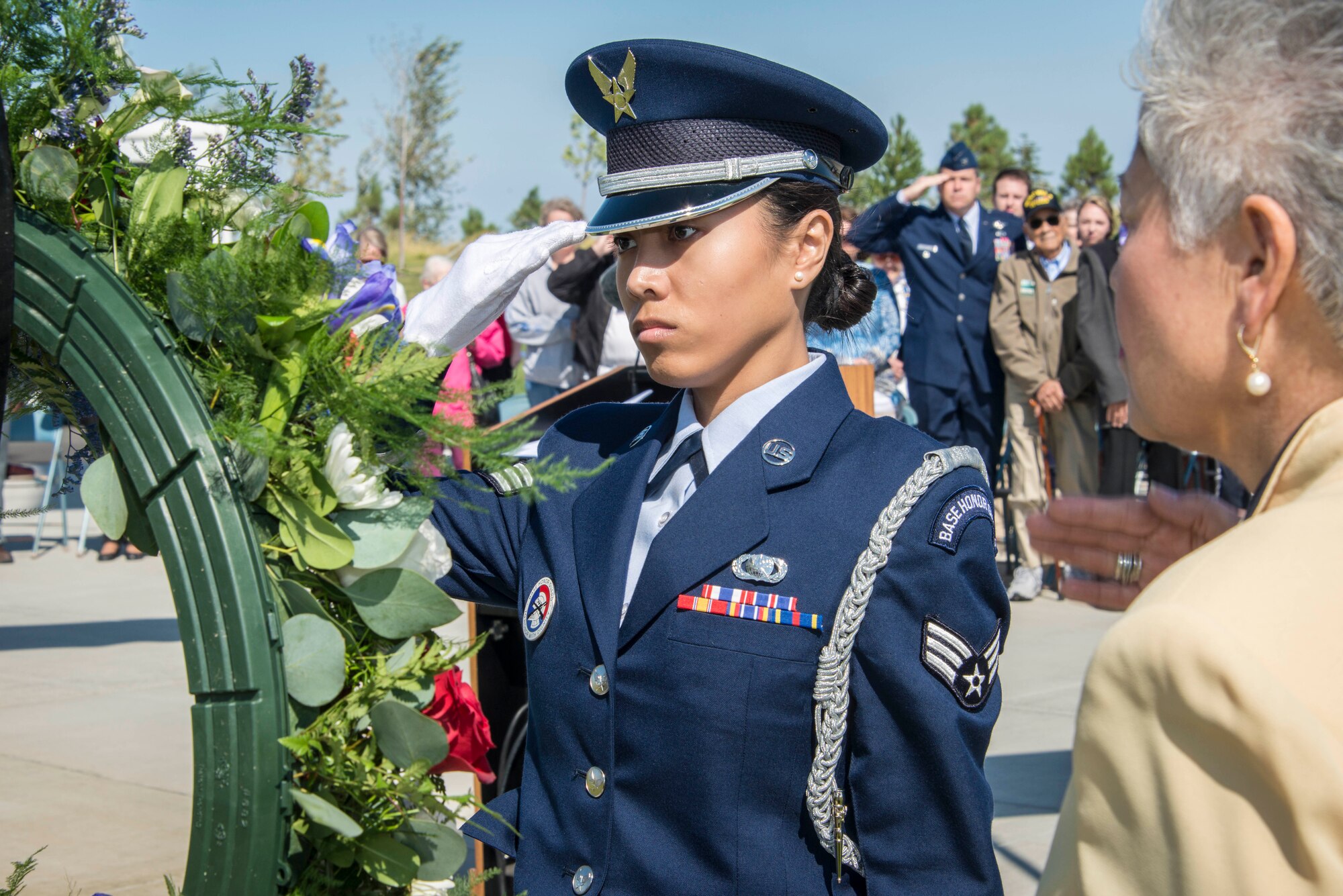 Senior Airman Janelle Patiño, Fairchild Honor Guard member, and Alfie Alvarado, Washington State Department of Veterans Affairs director, salute the ceremonial wreath during the commemoration ceremony for the 70th anniversary to the end of World War II Aug. 15, 2015, at the Washington State Veterans Cemetery in Medical Lake, Wash. Col. Matthew Fritz, 92nd Air Refueling Wing vice commander, can be seen in the background also saluting and flanked by WWII veterans and their families. The gift of flowers at a memorial site is a ritual that occurs around the world and understood in nearly every culture. The floral tributes at funeral bespeak both the beauty and the brevity of life and evoke memories of other days. (U.S. Air Force photo/Staff Sgt. Benjamin W. Stratton)