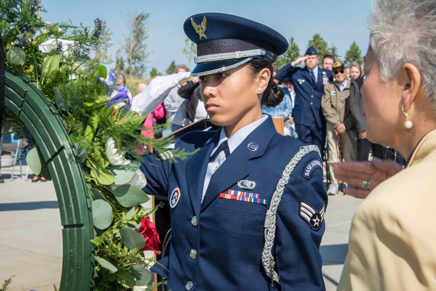 Senior Airman Janelle Patiño, Fairchild Honor Guard member, and Alfie Alvarado, Washington State Department of Veterans Affairs director, salute the ceremonial wreath during the commemoration ceremony for the 70th anniversary to the end of World War II Aug. 15, 2015, at the Washington State Veterans Cemetery in Medical Lake, Wash. Col. Matthew Fritz, 92nd Air Refueling Wing vice commander, can be seen in the background also saluting and flanked by WWII veterans and their families. The gift of flowers at a memorial site is a ritual that occurs around the world and understood in nearly every culture. The floral tributes at funeral bespeak both the beauty and the brevity of life and evoke memories of other days. (U.S. Air Force photo/Staff Sgt. Benjamin W. Stratton)