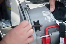 Lindsay Andersen, Delaware Office of Highway Safety fitting station coordinator, shows the location of the expiration date on a car seat Aug. 18, 2015, at the Child Development Center on Dover Air Force Base, Del. After a car seat has expired, it is best to destroy the car seat by cutting the straps, stripping the fabric and breaking the seat; this ensures the use of expired and unsafe car seats is hindered. (U.S. Air Force photo/Senior Airman Jared Duhon)