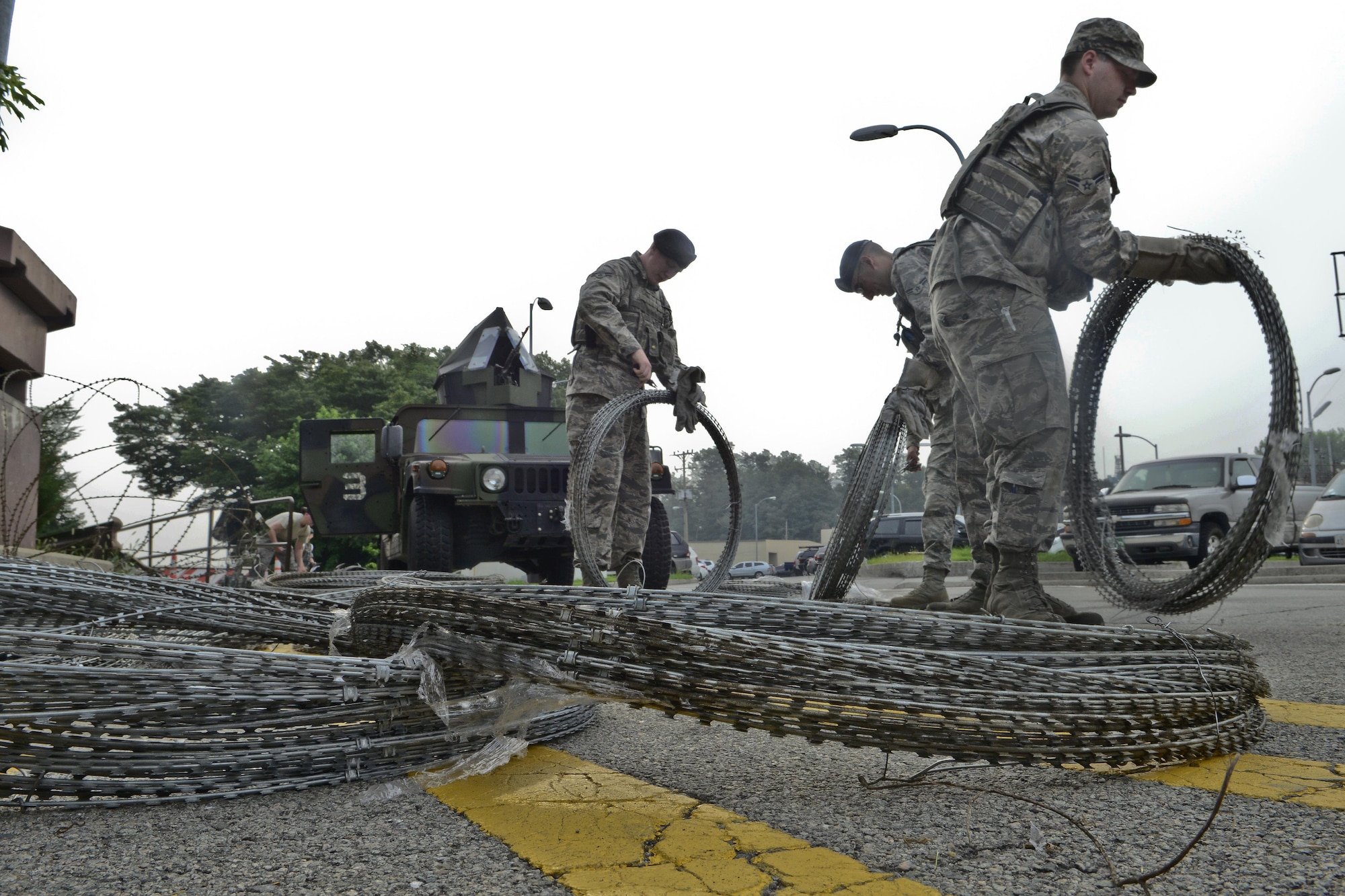 Concertina wire is laid out to establish barriers during exercise Beverly Midnight 15-03 on Osan Air Base, Republic of Korea, Aug. 18, 2015. During the exercise, Osan Airmen were tested on their ability to utilize their chemical, biological, radiological and nuclear training as well as administer self-aid and buddy care during contingency operations. (U.S. Air Force photo/Senior Airman Kristin High)