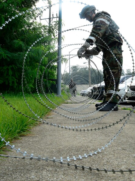 Airman 1st Class Quintan Ortega, 51st Security Forces Squadron patrolman, lays down concertina wire around a barrier during exercise Beverly Midnight 15-03 on Osan Air Base, Republic of Korea, Aug. 18, 2015.  The concertina wire is used to add extra reinforcement in the event of a ground attack. (U.S. Air Force photo/Senior Airman Kristin High)