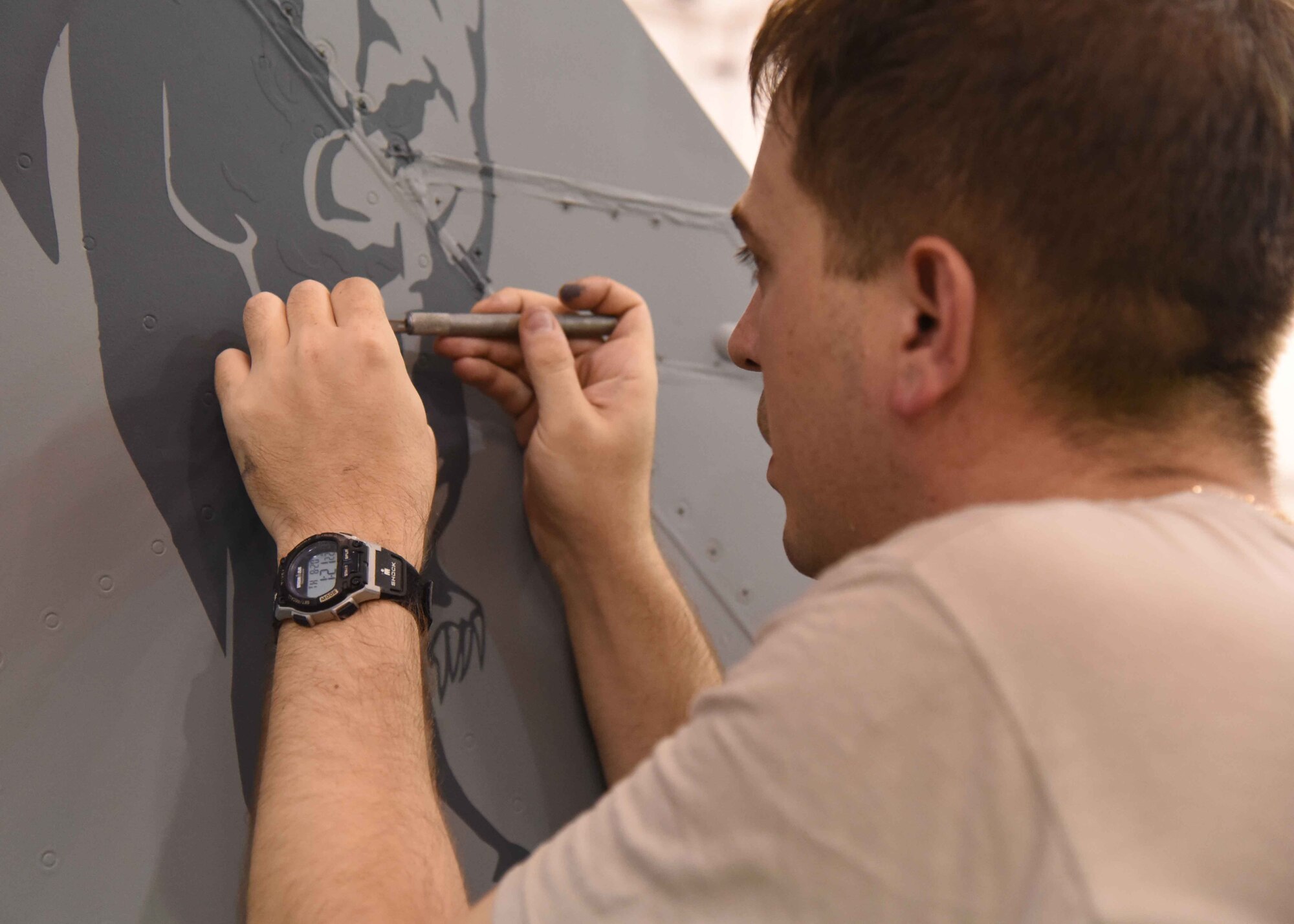 Tech. Sgt. Adam Corey, 35th Maintenance Squadron NCO in charge of corrosion control, removes excess decal paint on an F-16 Fighting Falcon’s tail fin at Misawa Air Base, Japan, Aug. 20, 2015. The decal is painted with polyurethane -- a sturdy chemical agent -- ensuring both the emblem and aircraft’s structural integrity is left uncompromised by weather or gravitational forces. (U.S. Air Force photo by Senior Airman Patrick S. Ciccarone/Released)