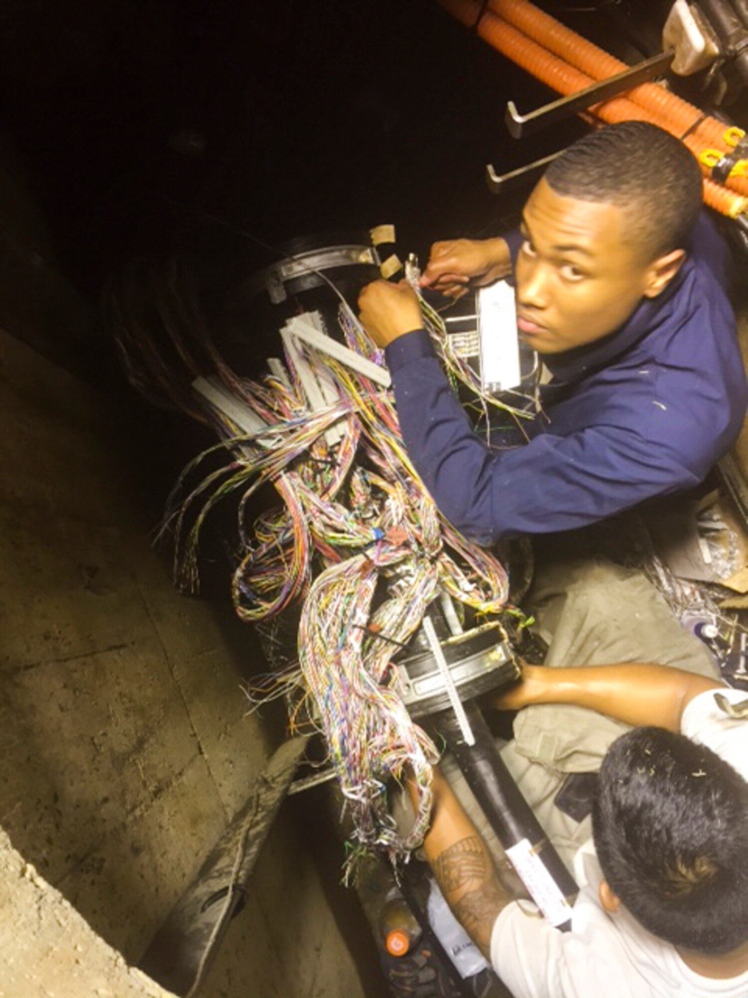 Airmen with the 374th Communications Squadron splice copper communications cables at Yokota Air Base, Japan. The 374 CS cable shop worked 67 hours in 4 days in two manholes and multiple buildings to repair a major downed communications cable. (Courtesy photo)