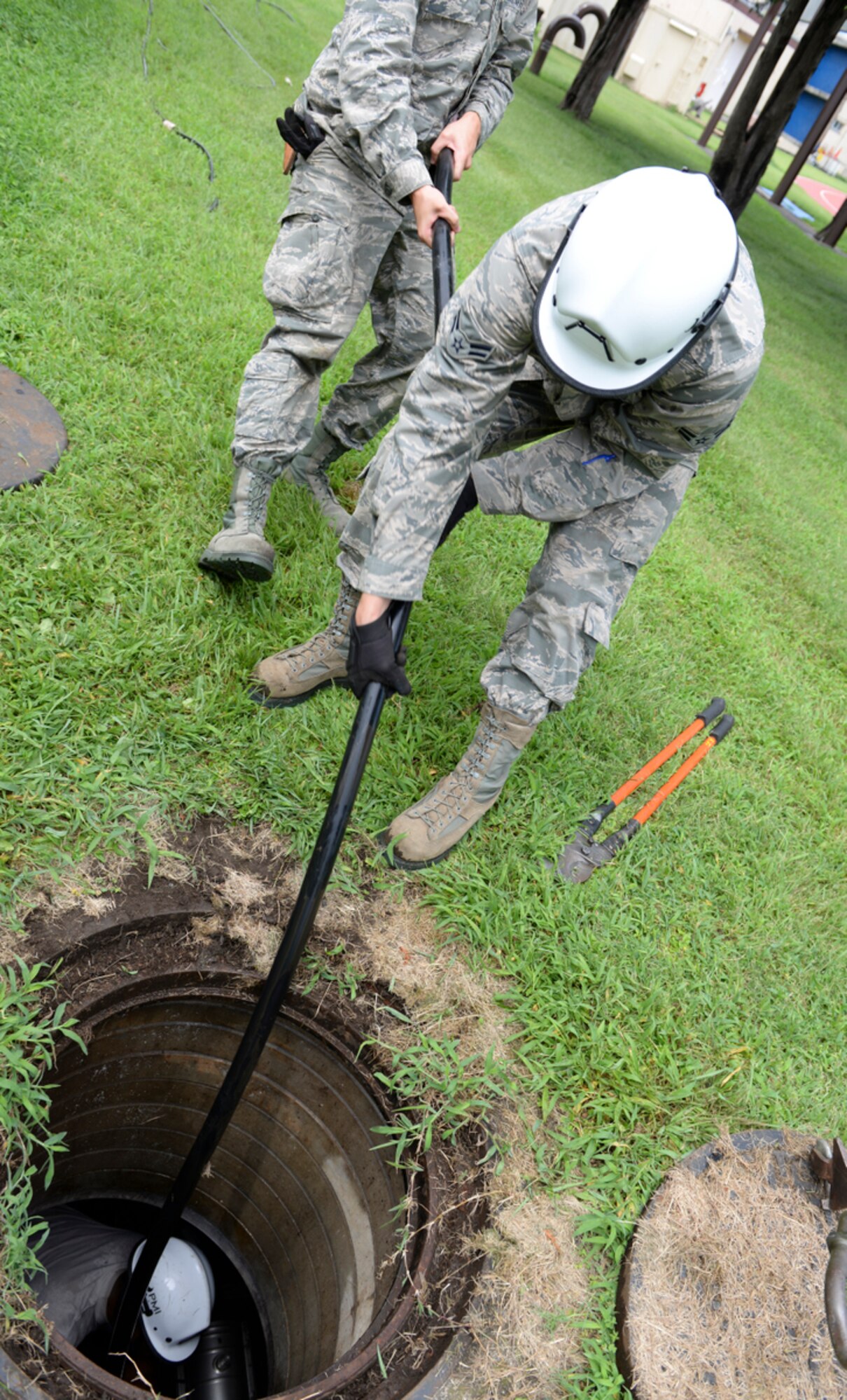 374th Communications Squadron Airmen pull old copper cable out of a manhole at Yokota Air Base, Japan, Aug. 18, 2015.  The 374 CS replaced 15,000 ft. of old cable with fiber optics, a project which took about five months. (U.S. Air Force photo by Airman 1st Class Elizabeth Baker/Released)