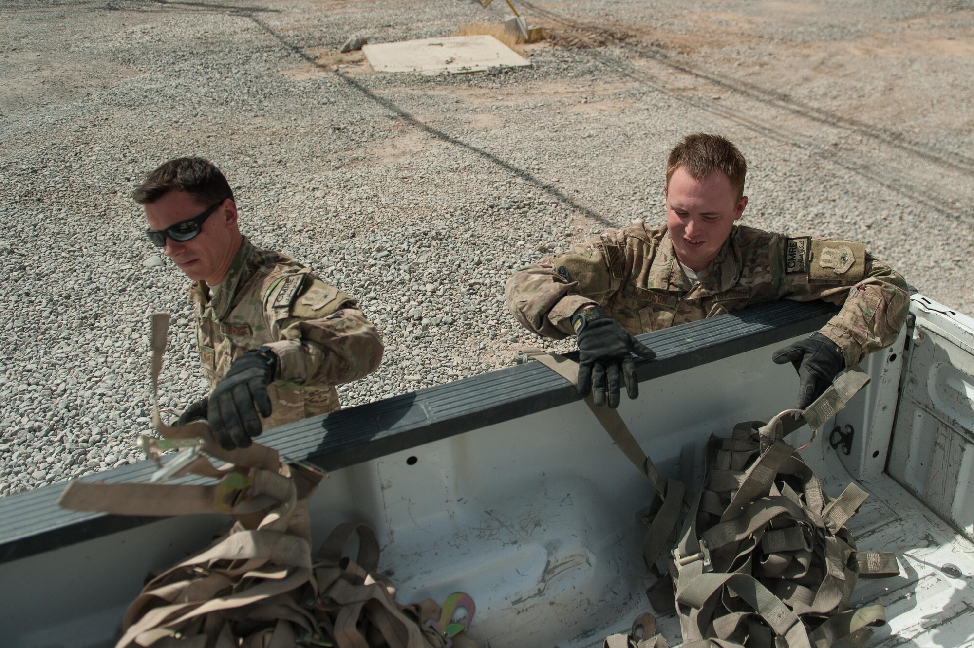 U.S. Air Force Staff Sgt. Cody Madison, right, 451st Expeditionary Support Squadron Central Command Material Recovery Element joint inspector, places cargo straps into the back of a truck at Kandahar Airfield, Aug. 15, 2015. Madison is responsible for identifying, storing and redeploying assets to the U.S. or disposing of items located throughout Afghanistan. (U.S. Air Force photo by Tech. Sgt. Joseph Swafford/Released)