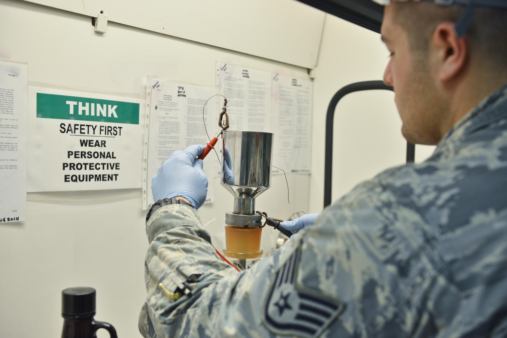 Staff Sgt. David Ramirez, 379th Expeditionary Logistic Readiness fuels laboratory, places grounded cables onto a funnel before pouring jet petroleum 8 through during a fuels testing August 18, 2015 at Al Udeid Air Base, Qatar. During a bottle test, technicians ground their equipment to reduce static that could cause a spark and ignite the fuel. (U.S. Air Force photo/ Staff Sgt. Alexandre Montes)  