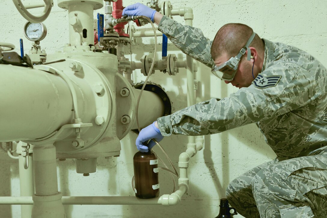Staff Sgt. David Ramirez, 379th Expeditionary Logistic Readiness fuels laboratory, extracts a sample of jet petroleum 8 from a pipeline which supplies the aircraft here August 19, 2015 at Al Udeid Air Base, Qatar. The base fuels laboratory at Al Udeid tests all petroleum that is used in aircraft, vehicles and generators throughout the installation to safeguard its quality, performance and safety. (U.S. Air Force photo/ Staff Sgt. Alexandre Montes)
