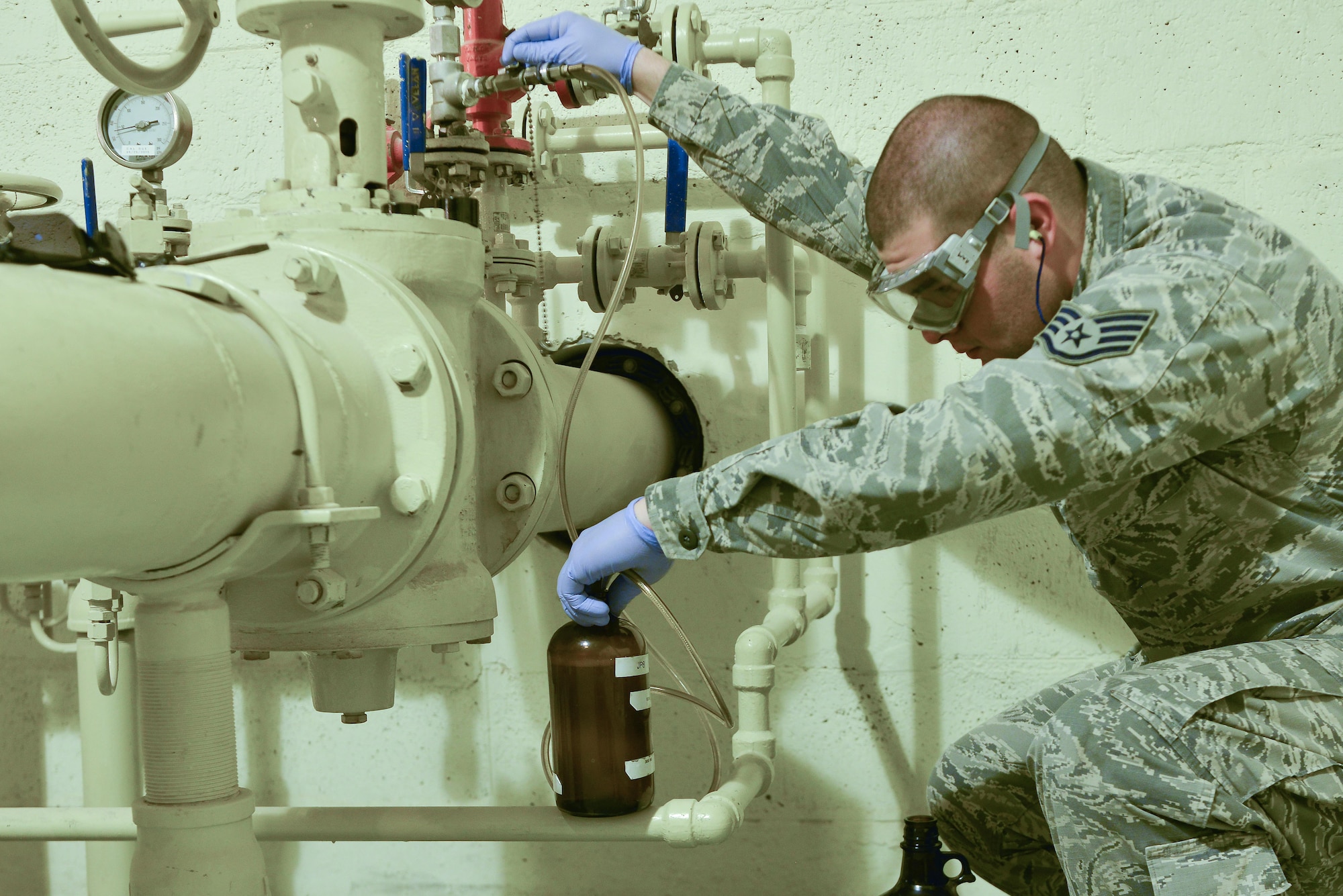 Staff Sgt. David Ramirez, 379th Expeditionary Logistic Readiness fuels laboratory, extracts a sample of jet petroleum 8 from a pipeline which supplies the aircraft here August 19, 2015 at Al Udeid Air Base, Qatar. The base fuels laboratory at Al Udeid tests all petroleum that is used in aircraft, vehicles and generators throughout the installation to safeguard its quality, performance and safety. (U.S. Air Force photo/ Staff Sgt. Alexandre Montes)