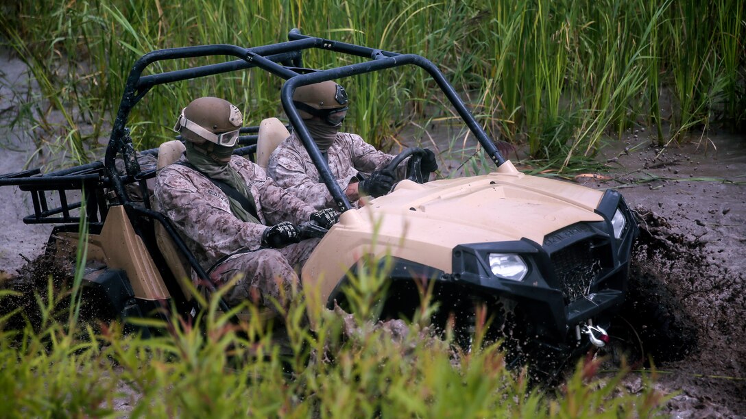 Marines with Force Reconnaissance Platoon, 22nd Marine Expeditionary Unit, drive through a fording pit during an all - terrain vehicle course at Marine Corps Base Camp Lejeune, North Carolina, Aug. 18, 2015. Marines drove the Polaris Rzr tactical vehicles through a water pit to gain experience with vehicle handling in swampy terrain.