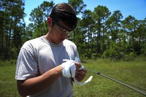 Senior Airman Taylor Carrasco, 1st Special Operations Civil Engineer explosive ordnance disposal journeyman, ties flagging ribbon to detonating cord before a pyrotechnic demonstration on Hurlburt Field, Fla., Aug. 5, 2015. Chaplain candidates had the opportunity to view the effects of explosives, speak with experienced EOD technicians about resiliency and try on bomb suits during their visit. (U.S. Air Force photo/ Senior Airman Meagan Schutter)