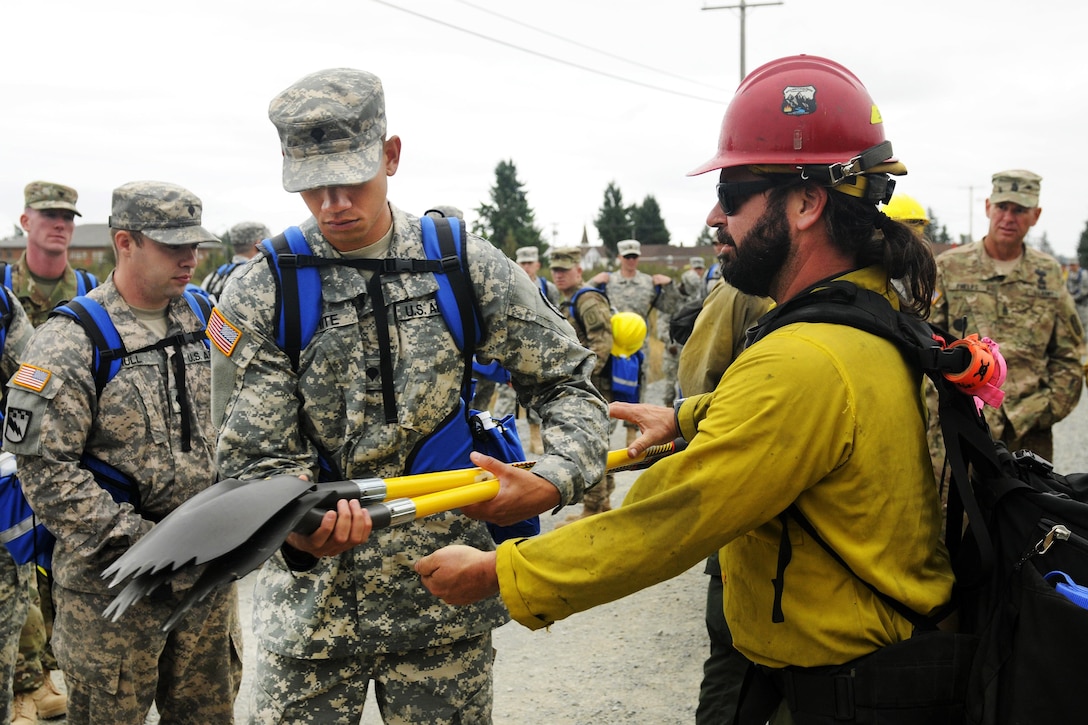 A civilian firefighter issues equipment to soldiers before they train to fight fires near Joint Base Lewis-McChord, Wash., Aug. 20, 2015. The soldiers are assigned to 5th Battalion, 3rd Field Artillery Regiment, 17th Field Artillery Brigade. The soldiers received two days of guidance, including classroom instruction and hands-on training, to prepare them to suppress wildfires burning across the Pacific Northwest. 
