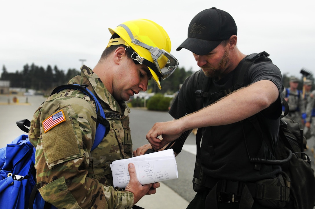Army 1st Lt. Rory Cunningham, left, reviews the configuration of a radio with Nick Lee, a crew boss assigned to the team, before conducting firefighting training on Joint Base Lewis-McChord, Wash., Aug. 20, 2015. Cunningham, a firefighting team leader, is assigned to  5th Battalion, 3rd Field Artillery Regiment, 17th Field Artillery Brigade. He is on one of 10 teams training to react to wildfires burning the Pacific Northwest. U.S. Army photo by Sgt. 1st Class Andrew Porch