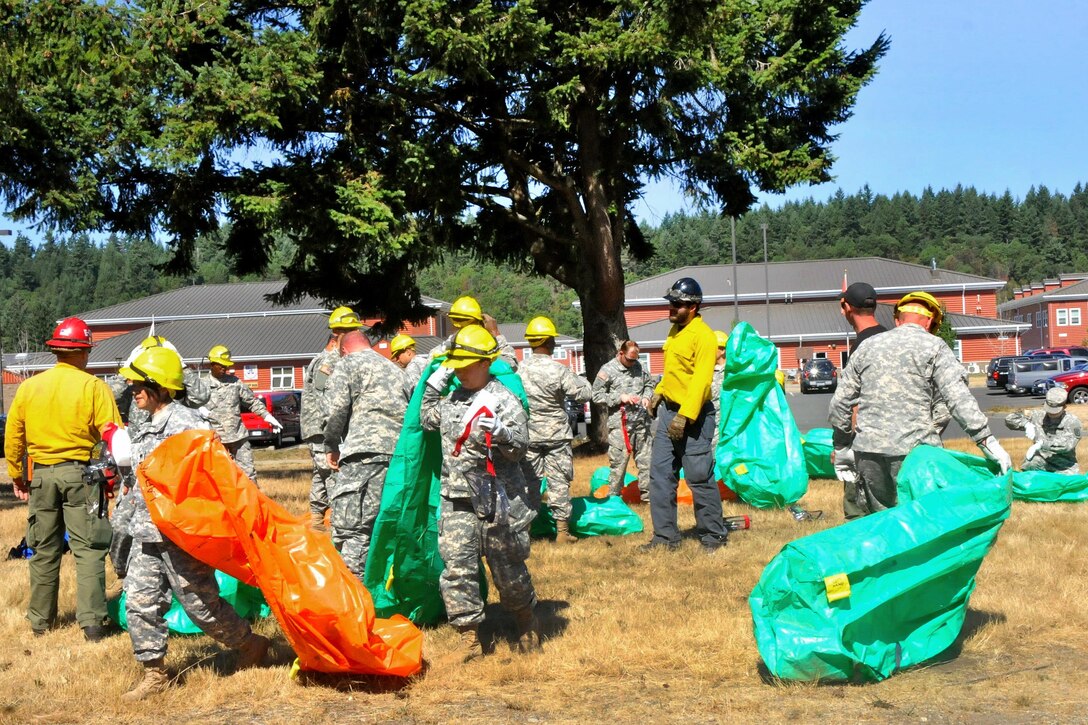 Soldiers practice firefighting techniques with their personnel protective equipment as they prepare to serve as firefighters to assist the National Interagency Fire Center on Joint Base Lewis-McChord, Wash., Aug. 19, 2015. U.S. Army photo by Sgt. Quanesha Deloach
