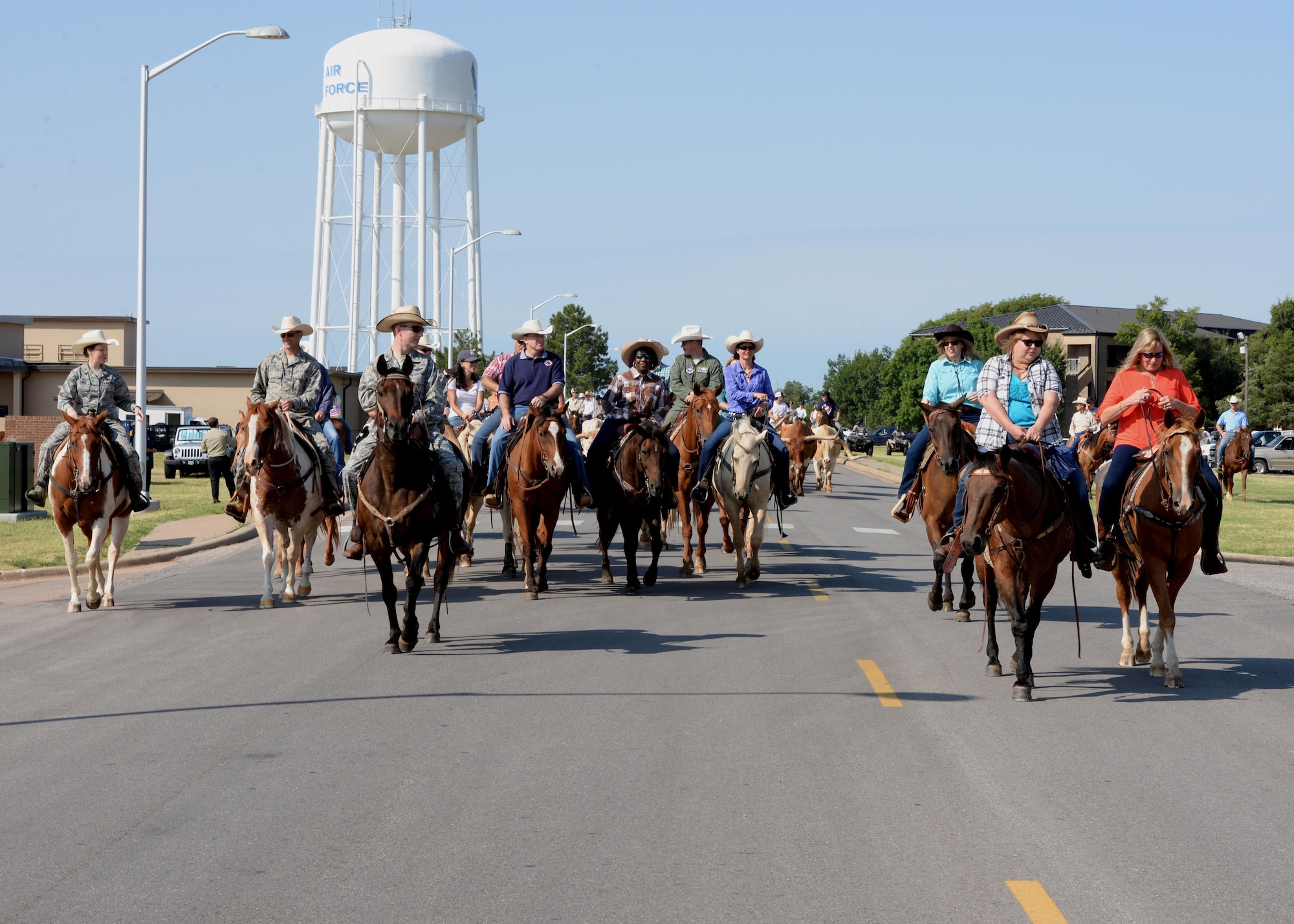 A herd of longhorn cattle are led through the streets of Altus Air Force Base, Oklahoma, by local ranchers and riders during the annual Altus AFB cattle drive, Aug. 20, 2015. The cattle drive tradition started in 1999 with 15 riders and a herd of roughly 30 longhorn cattle parading through the streets of Altus AFB. (U.S. Air Force photo by Airman 1st Class Megan E. Acs)