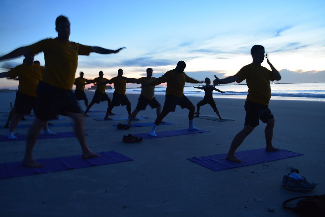 Mia Kuhn, MWR fitness specialist, leads a group of Sailors from Southeast Regional Maintenance Center in beach yoga at sunrise Aug. 19.   Kuhn and the MWR Fitness Center offer yoga, TRX suspension training and other new workouts to allow Sailors a different, more holistic approach to mental and physical fitness. 