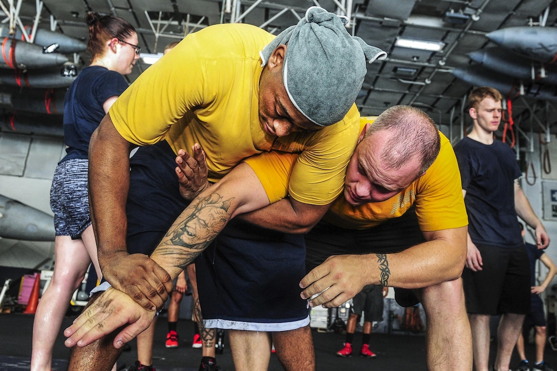 U.S. Navy Petty Officer 2nd Class Jamall Shuford performs a mechanical advantage control hold on Master-at-Arms 1st Class Joey Lawrence during a security forces training class in the hangar bay aboard the aircraft carrier USS Theodore Roosevelt in the Arabian Gulf, Aug. 20, 2015. The carrier is in the U.S. 5th Fleet area of operations supporting Operation Inherent Resolve, which include strike operations in Iraq and Syria as directed. U.S. Navy photo by Petty Officer 3rd Class Taylor L. Jackson 