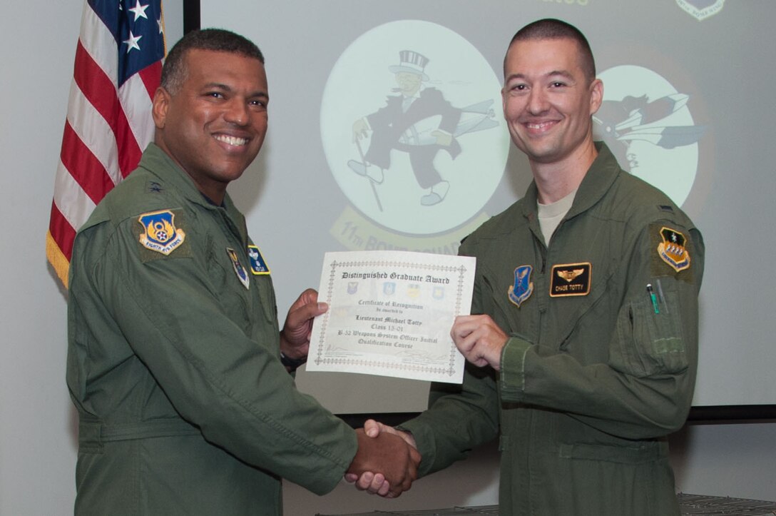 U.S. Air Force, Major General Richard Clark, commander of 8th Air Force, presents the Weapons Systems Officer Distinguished Graduate Award to 1st Lt. Michael Totty during a Formal Training Unit (FTU) graduation ceremony, Aug. 19, 2015, Barksdale Air Force Base, La. Toddy graduated from the FTU as an Electronic Warfare Officer on the B-52H Stratofortress. (U.S. Air Force photo by Master Sgt. Laura Siebert /Released)