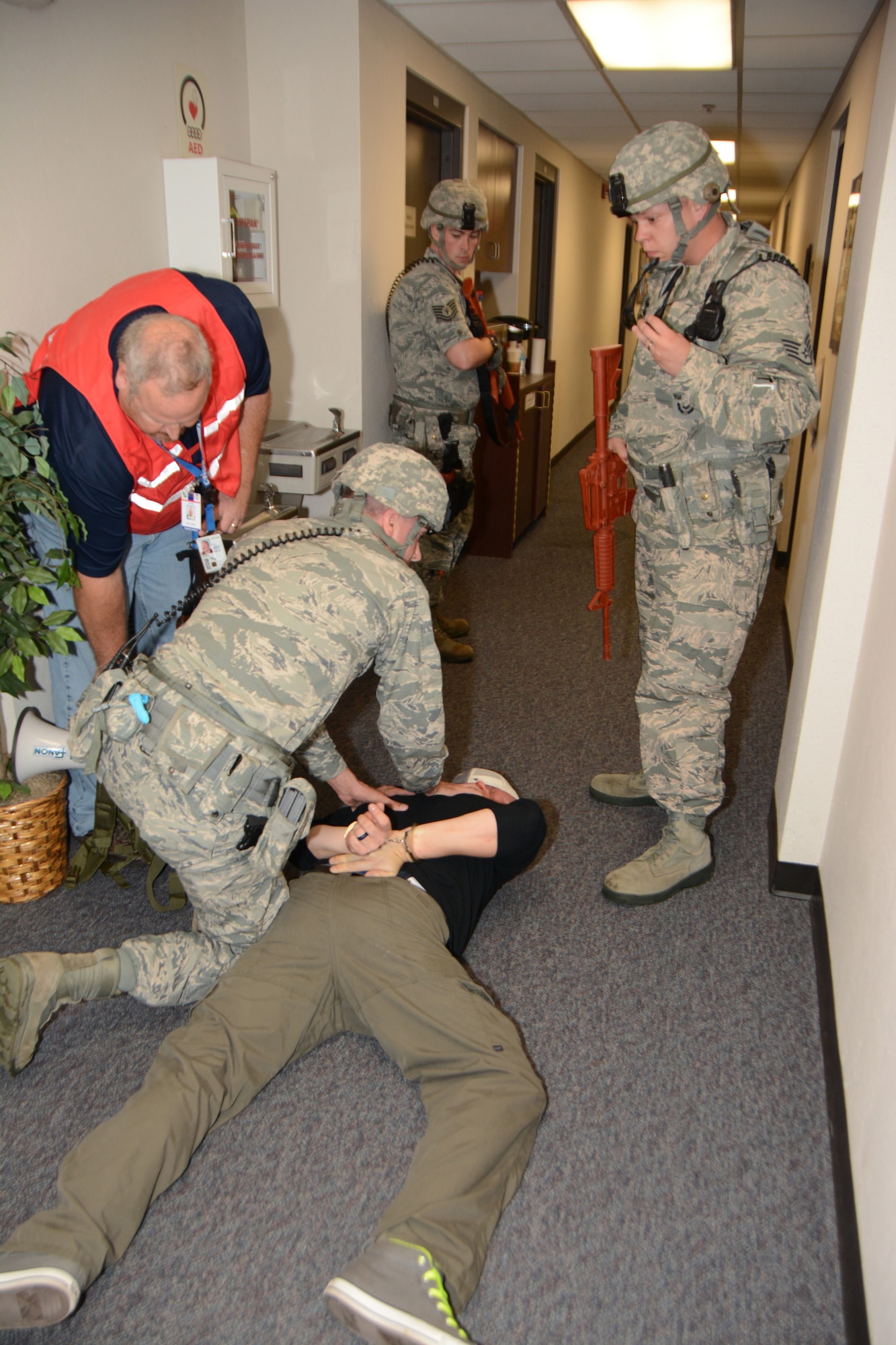 Airmen from the 72nd Security Forces Squadron work together during an active shooter exercise to detain mock shooter, Tech. Sgt. Darryl Lindgens, Aug. 12 in the 507th Air Refueling Wing headquarters building as senior controller Scott Lindsey, with the 72nd ABW Inspector General Inspections, evaluates. This is the third active shooter exercise performed on Tinker Air Force Base this year. (Air Force photo by Staff Sgt. Lauren Gleason)