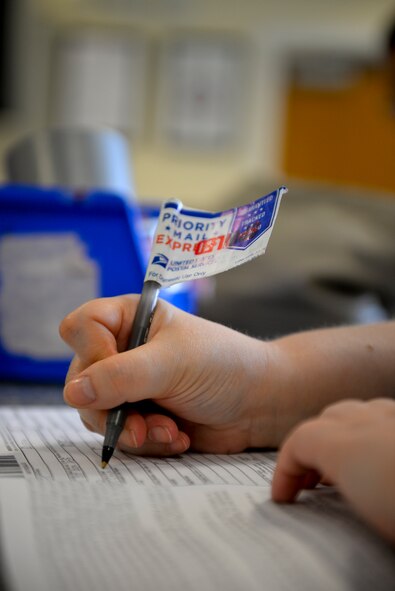 Aimee Evans, 488th Intelligence Squadron language analyst from Cleveland, fills out a customs form Aug. 19, 2015, at the base post office on RAF Mildenhall, England. On Oct. 1, 2015, the United States Postal Service will only accept customs forms that have been printed out. To help ease the transition the base post office will start implementing the process on Sept. 1, 2015. (U.S. Air Force photo by Staff Sgt. Micaiah Anthony/Released)