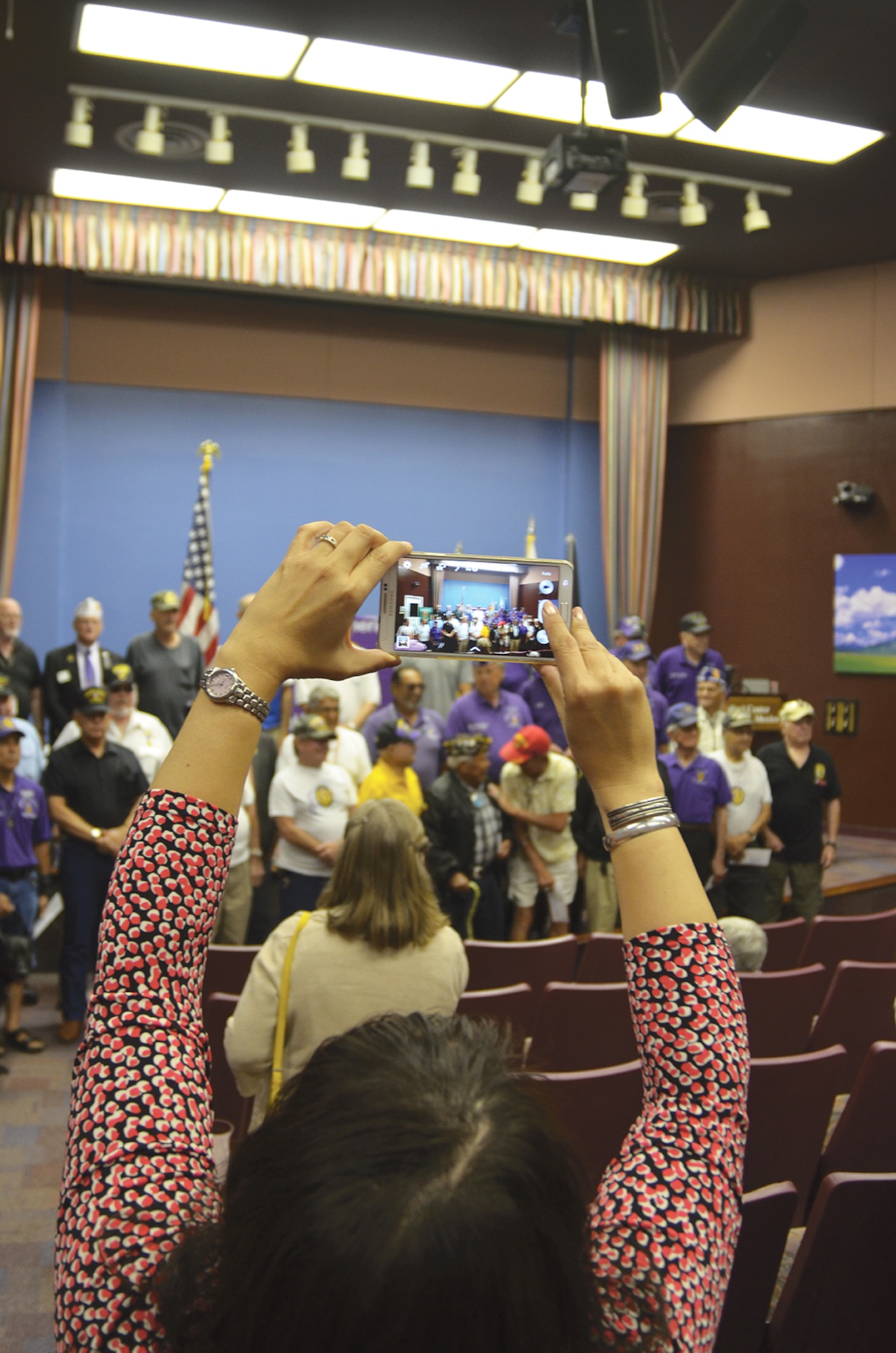 An attendee snaps a photo with her cell phone during a ceremony to honor Purple Heart recipients. Around 75 people attended the Aug. 13 event at the VA center’s Education Auditorium, which was held in honor of those who were injured in combat. (Photo by Lee Ross)