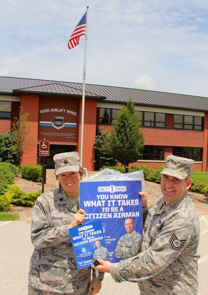 Lt. Col. Grace Chapin, 932nd Airlift Wing Inspector General, gets a recruiting poster featuring the commander, Col. Karl Goerke, from recruiter Tech. Sgt. Paul Condor in front of the wing's headquarters building.  (U.S. Air Force photo by Maj. Stan Paregien)