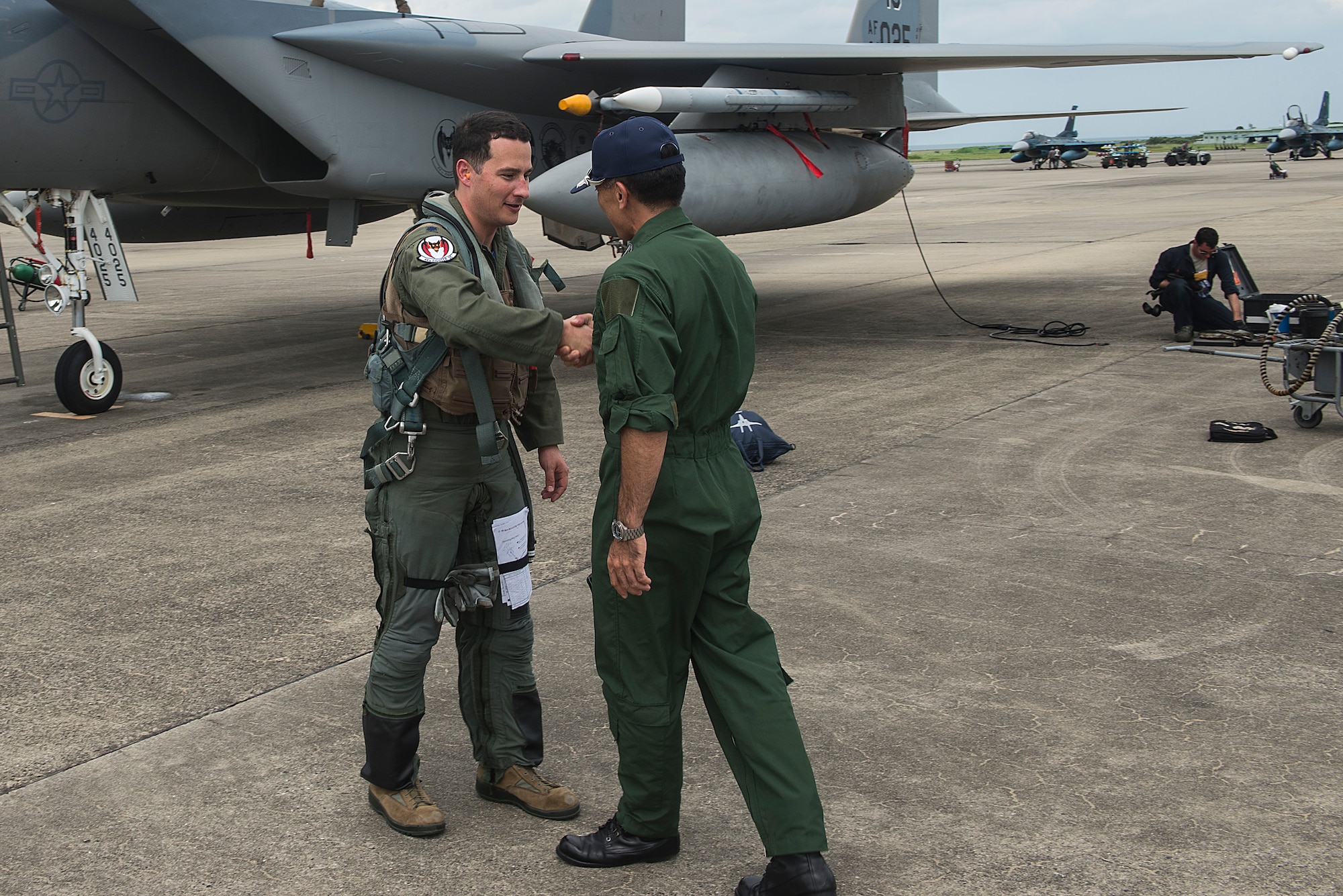Japanese Air Self-Defense Force Col. Hirohisa Takakusaki, 8th Air Wing Operations Group commander, greets U.S. Air Force Lt. Col. Kevin Jamieson, 44th Fighter Squadron commander, at Tsuiki Air Base, Japan, Aug. 21, 2015. More than 150 Airmen from the 18th Wing and the first group of F-15 Eagles from the 44th Fighter Squadron began Aviation Training Relocation today at Tsuiki Air Base, Japan. (U.S. Air Force photo by Senior Airman Stephen G. Eigel)