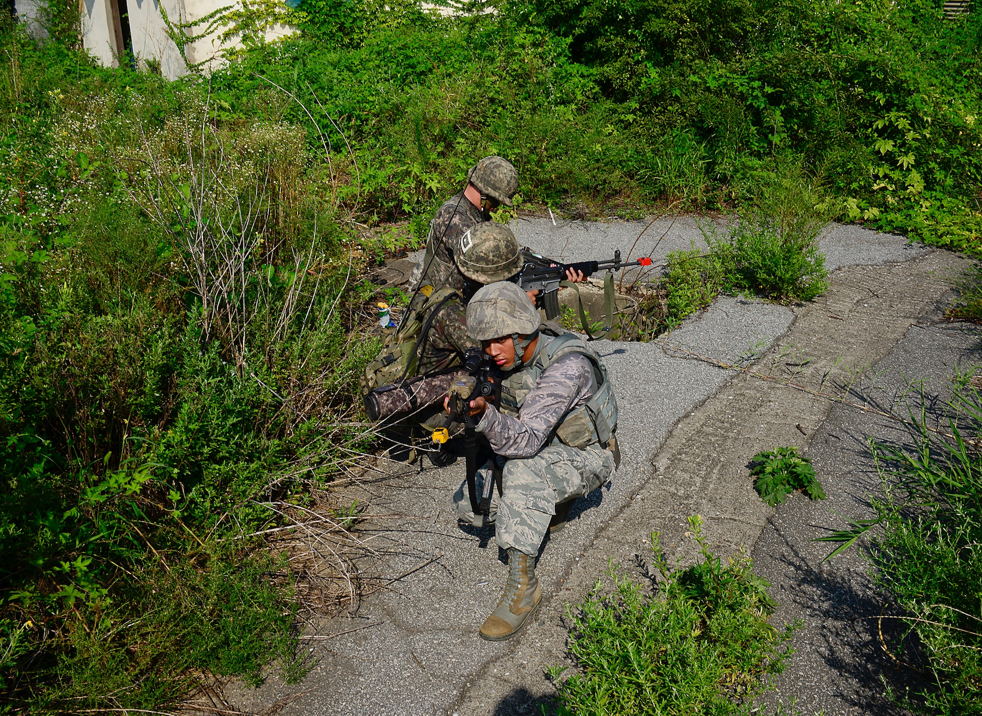 Airman 1st Class Donte Estes, 51st Security Forces Squadron patrolman, and a Republic of Korea army soldier, 4th Battalion 169th Regiment, provide cover during a joint mission as part of readiness exercise, Beverly Midnight 15-03, in a training area outside Osan Air Base, ROK, Aug. 18, 2015. Joint training exercises allow the 51st SFS to share their skills and knowledge of the region surrounding the base with their ROKA counterparts. (U.S. Air Force photo/Senior Airman Kristin High)