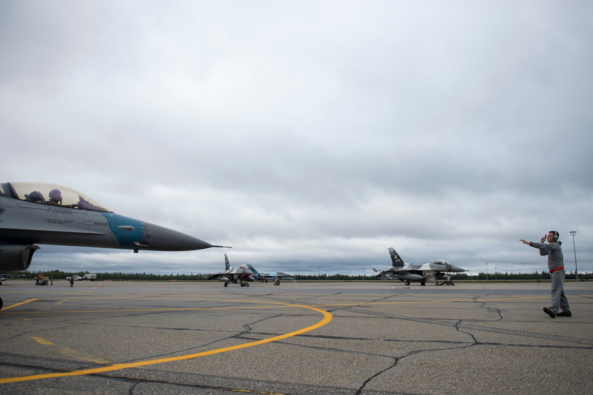 U.S. Air Force Airman 1st Class Jason Watson, a 354th Aircraft Maintenance Squadron crew chief, marshals an 18th Aggressor Squadron F-16 Fighting Falcon to taxi, Aug. 19, 2015, prior to the launch of a RED FLAG-Alaska (RF-A) 15-3 sortie from Eielson Air Force Base, Alaska. The support of the 354th Maintenance Group’s Airmen ensure the pilots of the 18th Aggressor Squadron can act as enemy “Red” forces to employ real-world tactics that require coalition “Blue” forces to adjust quickly, work together and overcome challenges during simulated combat sorties throughout RF-A. (U.S. Air Force photo by 1st Lt. Elias Zani/Released