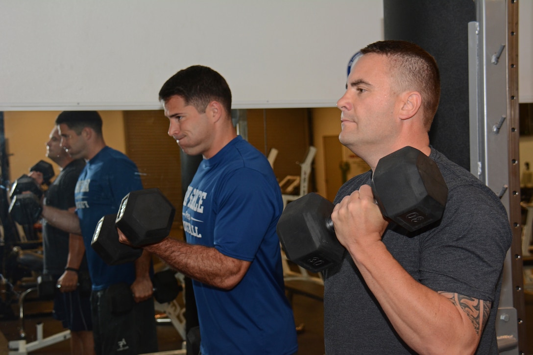 Air Force Senior Master Sgt. Claus Peris, right, 60th Aircraft Maintenance Squadron aircraft maintenance unit superintendent, performs bicep curls with Air Force 1st Lt. Mike DeWitt, 60th AMXS aircraft maintenance unit officer in charge, in the 60th AMXS gym at Travis Air Force Base, Calif., June 16, 2015. Peris trains with DeWitt, a former U.S. Air Force Academy football player, four days a week. U.S. Air Force photo  by Tech. Sgt. James Hodgman