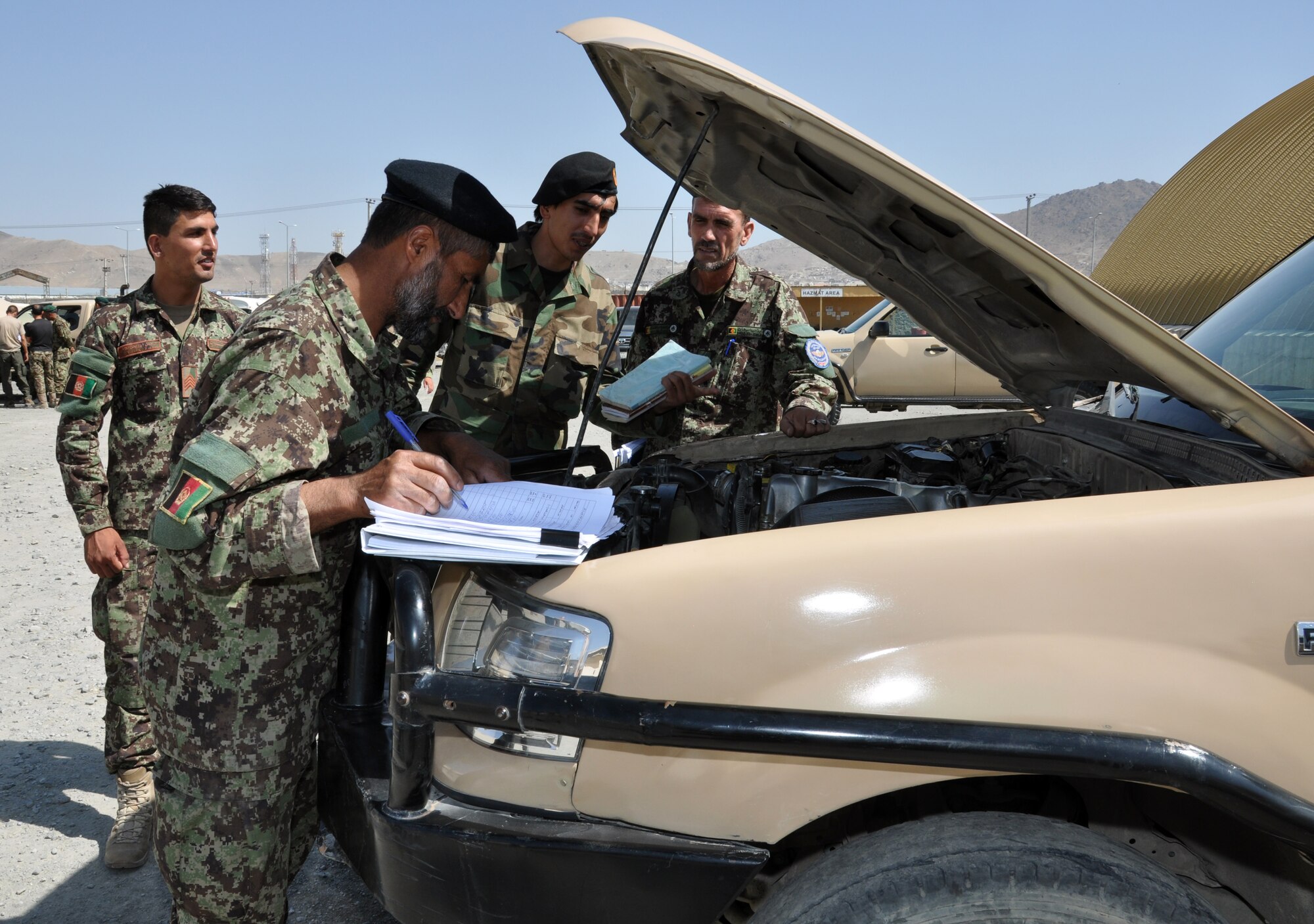 Afghan National Army and Afghan Air Force vehicle maintainers work a checklist during a training session at Kabul Air Wing Aug. 6, 2015. Train, Advise, Assist Command – Air (TAAC-Air) advisors and contractors work to refine Afghan Air Force logistics, reduce new acquisitions and programs, and create a sustainable and capable air force to support the Afghan National Security Forces in the coming years. The Vehicle Maintenance Training Program (VMTP) is one focus area to acquire coalition expertise to provide meaningful instruction on specialized equipment and contractor support to the AAF. They began training June 27, 2015. (U.S. Air Force photo by Capt. Eydie Sakura/Released)