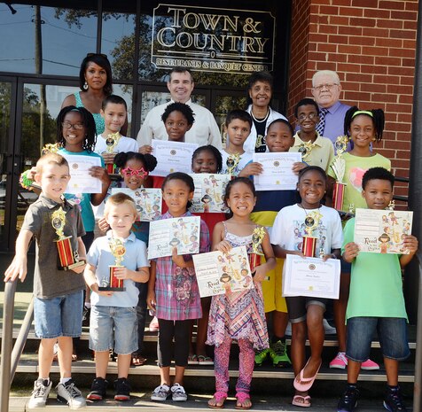 Officials pose with children who showcase their trophies and certificates following Marine Corps Logistics Base Albany’s 2015 Summer Reading Program awards ceremony, Aug. 22. Held at the installation’s Town and Country Restaurant Grand Ballroom, top readers in four different age groups received trophies and all of the participants received certificates as their parents watched or photographed them. 