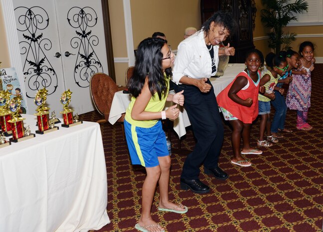 Guest speaker, Verda L. Parker, public affairs specialist, Public Affairs Office, sings and dances with children during Marine Corps Logistics Base Albany’s 2015 Summer Reading Program awards ceremony, Aug. 22. Held at the installation’s Town and Country Restaurant Grand Ballroom, top readers in four different age groups received trophies and all of the participants received certificates as their parents watched or photographed them. 
