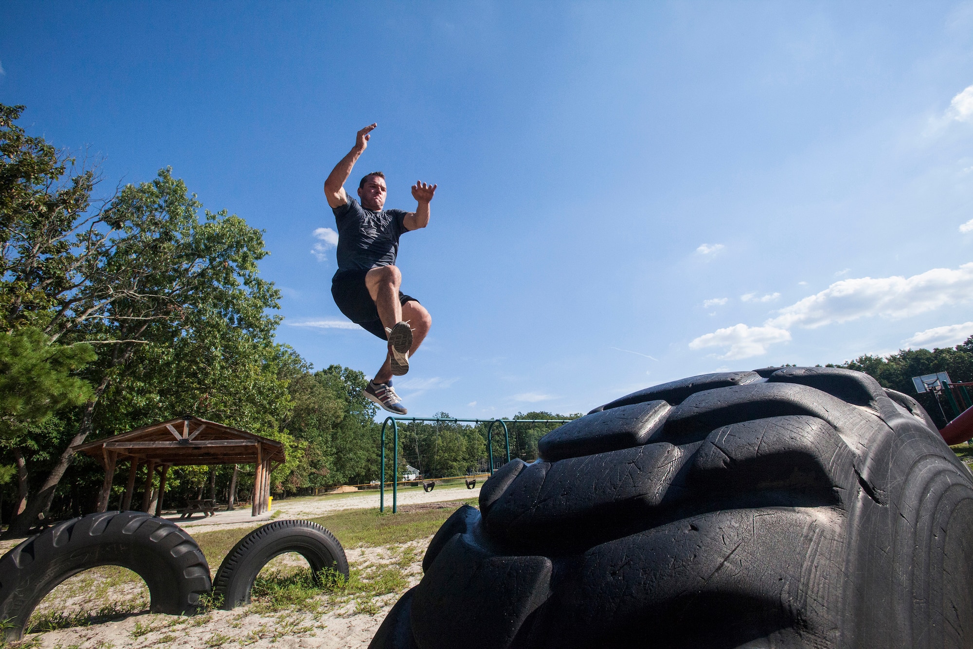 Tech. Sgt. Justin B. Gielski jumps from one tire to another while training to compete on the TV show “American Ninja Warrior” at a playground near his home in Medford, N.J., Aug. 21, 2015. Gielski placed fifth in the all-military city final on the TV show and advanced to the finals in Las Vegas. Gielski is a loadmaster with the 150th Special Operations Squadron, 108th Wing, New Jersey Air National Guard, located at Joint Base McGuire-Dix-Lakehurst, N.J. (U.S. Air National Guard photo by Master Sgt. Mark C. Olsen/Released)