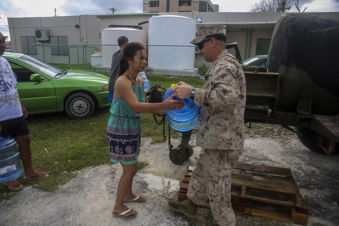 U.S. Navy Seaman Joshua Peffley hands water to a local woman as a part of a typhoon relief mission in Saipan Aug. 13, 2015. The Marines with Echo Company, Battalion Landing Team 2nd Battalion, 5th Marines, 31st Marine Expeditionary Unit and Combat Logistics Battalion 31, 31st MEU, assisted the locals of Saipan by producing and distributing potable water. The Marines and sailors of the 31st MEU were conducting training near the Mariana Islands when they were redirected to Saipan after the island was struck by Typhoon Soudelor Aug. 2-3. (U.S. Marine Corps photo by Cpl. Ryan C. Mains/Released)