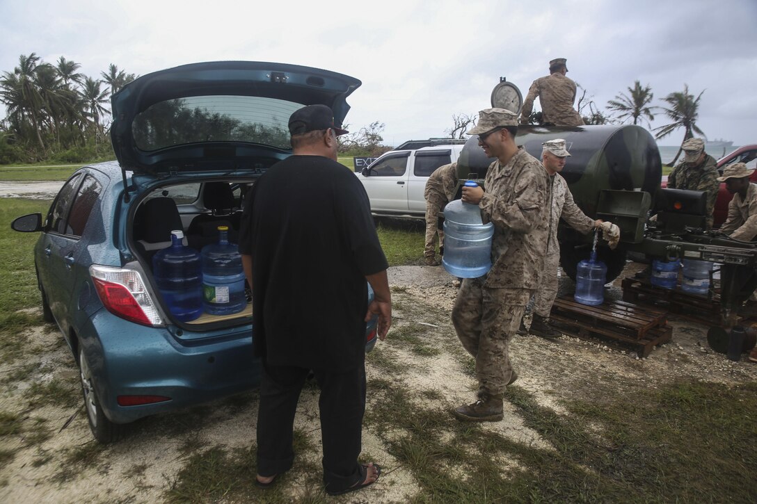 U.S. Marine Cpl. Darien Ramos hands a water jug to a local as a part of a typhoon relief mission in Saipan Aug. 15, 2015. The Marines with Echo Company, Battalion Landing Team 2nd Battalion, 5th Marines, 31st Marine Expeditionary Unit and Combat Logistics Battalion 31, 31st MEU, assisted the locals of Saipan by producing and distributing potable water. The Marines and sailors of the 31st MEU were conducting training near the Mariana Islands when they were redirected to Saipan after the island was struck by Typhoon Soudelor Aug. 2-3. (U.S. Marine Corps photo by Cpl. Ryan C. Mains/Released)