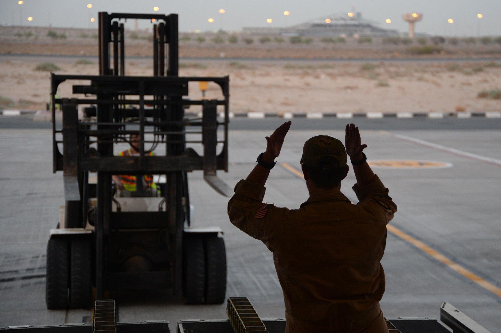 U.S. Air Force Senior Airman Rebecca, 816th Expeditionary Airlift Squadron loadmaster, guides a pay-loader to unload cargo on board a C-17 Globemaster III in support of Operation Inherent Resolve in Kuwait, August 14, 2015. OIR is the military intervention against Daesh. (U.S. Air Force photo by Staff Sgt. Sandra Welch)   