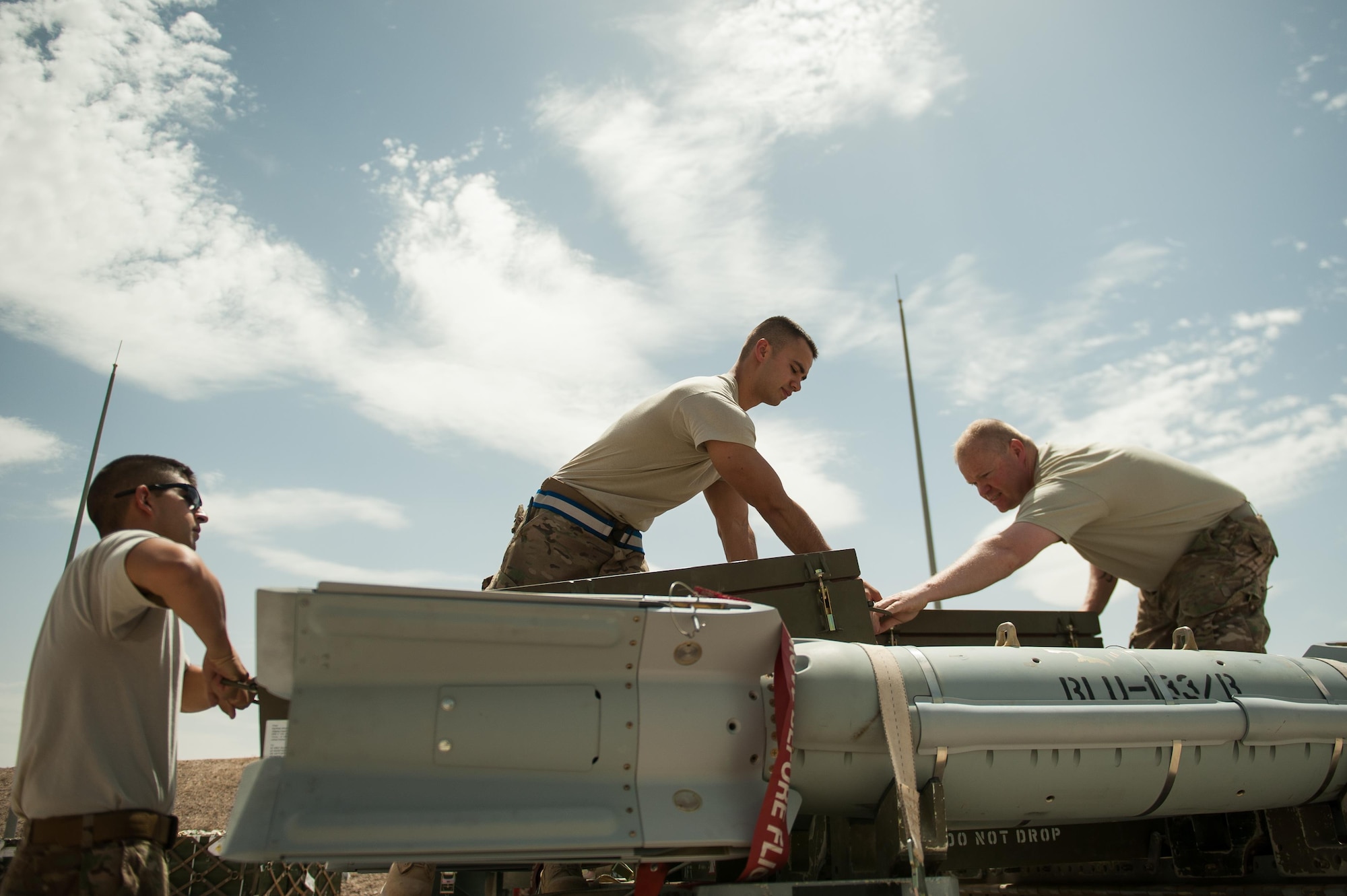 U.S. Air Force Airman 1st Class Matthew Lopez, center, 62nd Expeditionary Reconnaissance Squadron munitions systems technician, unpacks a GPS-guided GBU-49 weapon at Kandahar Airfield, Afghanistan, Aug. 15, 2015.  The 62nd ERS Munitions Flight ensures that every munition loaded onto an MQ-1 Predator and MQ-9 Reaper will perform as expected when used. (U.S. Air Force photo by Tech. Sgt. Joseph Swafford/Released)