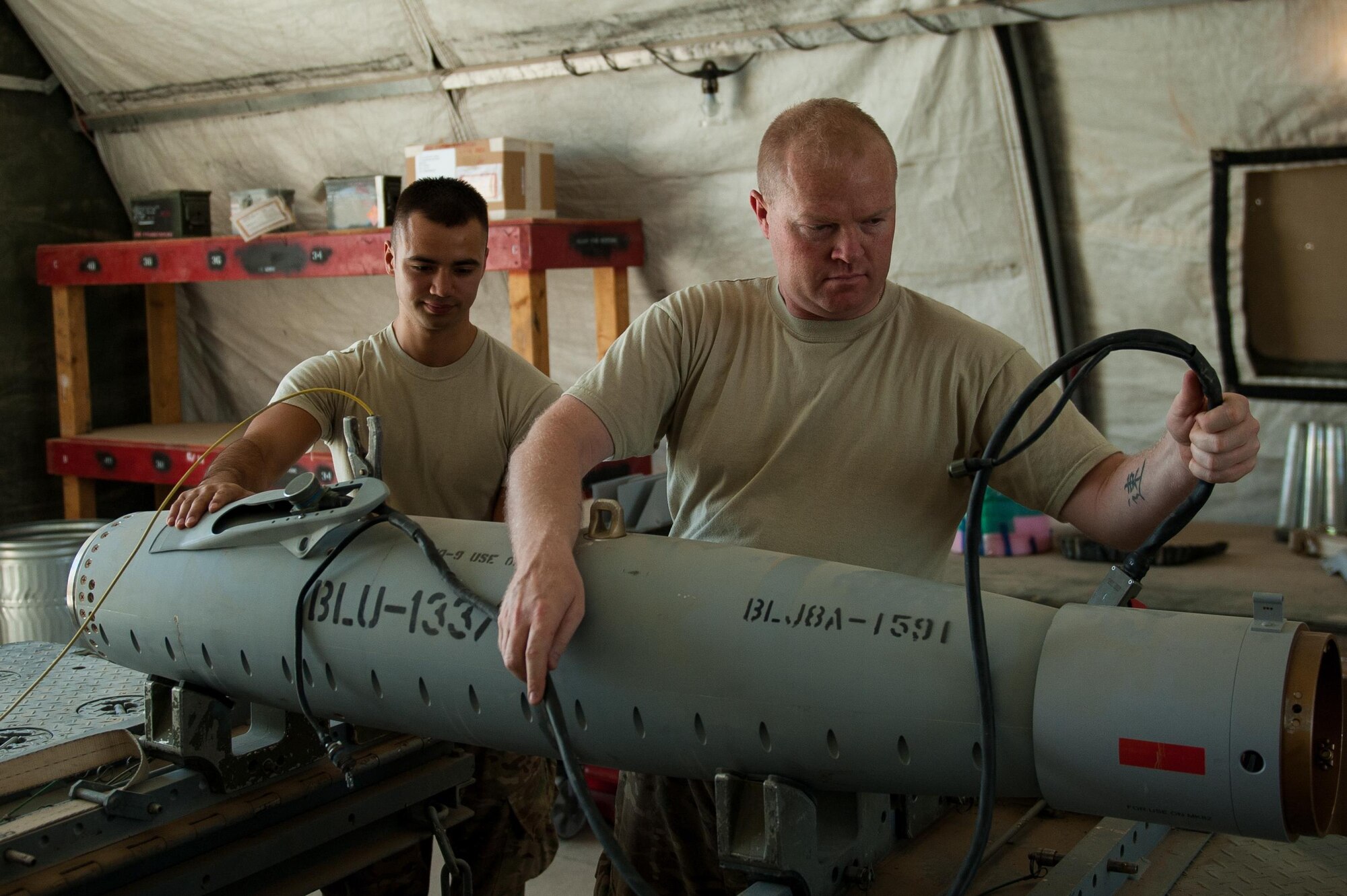 U.S. Air Force Airman 1st Class Matthew Lopez, left, 62nd Expeditionary Reconnaissance Squadron munitions systems technician, helps build a GPS-guided GBU-49 weapon at Kandahar Airfield, Afghanistan, Aug. 15, 2015.  The 62nd ERS Munitions Flight ensures that every munition loaded onto an MQ-1 Predator and MQ-9 Reaper will perform as expected when used. (U.S. Air Force photo by Tech. Sgt. Joseph Swafford/Released)