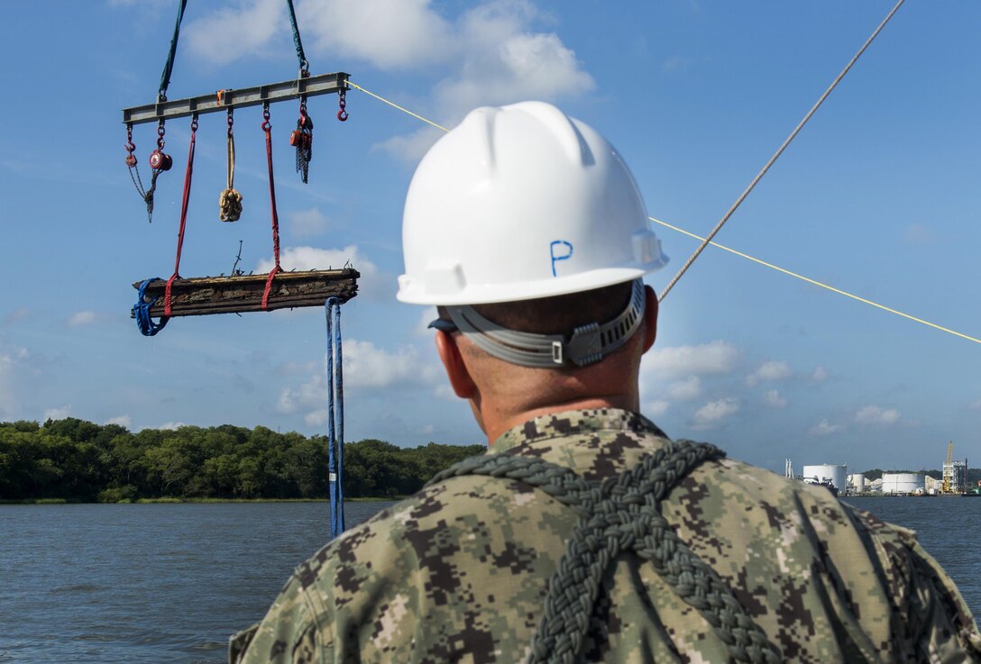 Navy Chief Warrant Officer 3 Jason Potts supervises as crews raise a piece of casemate, made of railroad ties and timber, from the Savannah River in Savannah, Ga., Aug. 14, 2015. The casemate was the steamship's outer layer of armor. Potts is an on scene commander, Task Element CSS Georgia steamship. U.S. Navy photo by Petty Officer 1st Class Blake Midnight