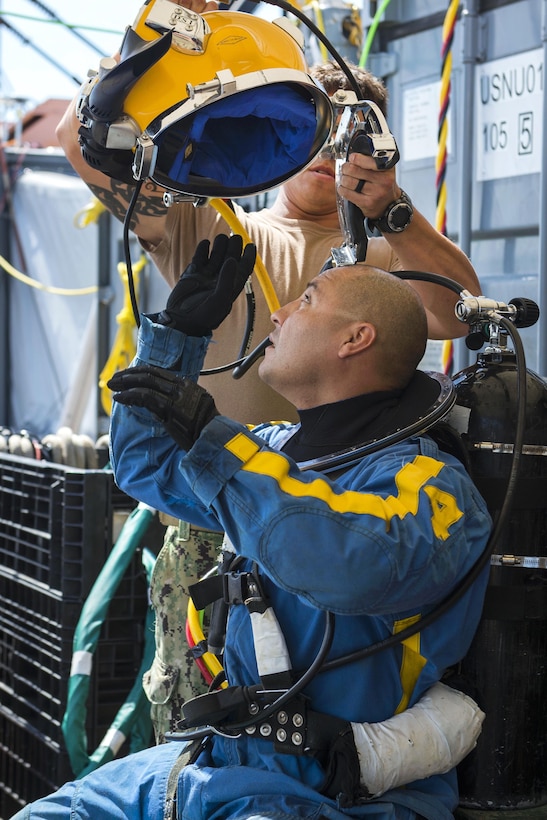 Navy Petty Officer 1st Class Fernando Almazan dons his KM-37 diving helmet before diving during salvage operations in the Savannah River in Savannah, Ga., Aug. 15, 2015. Almazan is a diver assigned to Mobile Diving and Salvage Unit 2. U.S. Navy photo by Petty Officer 1st Class Blake Midnight