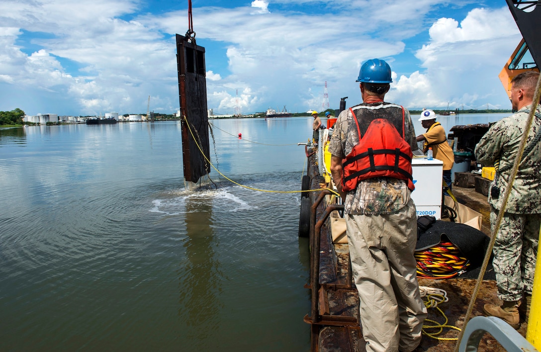 Navy divers and civilian workers assigned to the CSS Georgia salvage project watch as crews raise a 17,000-pound guillotine from the Savannah River in Savannah, Ga., Aug. 17, 2015. Crews used the guillotine to break up pieces of the steamship. U.S. Navy photo by Petty Officer 1st Class Blake Midnight