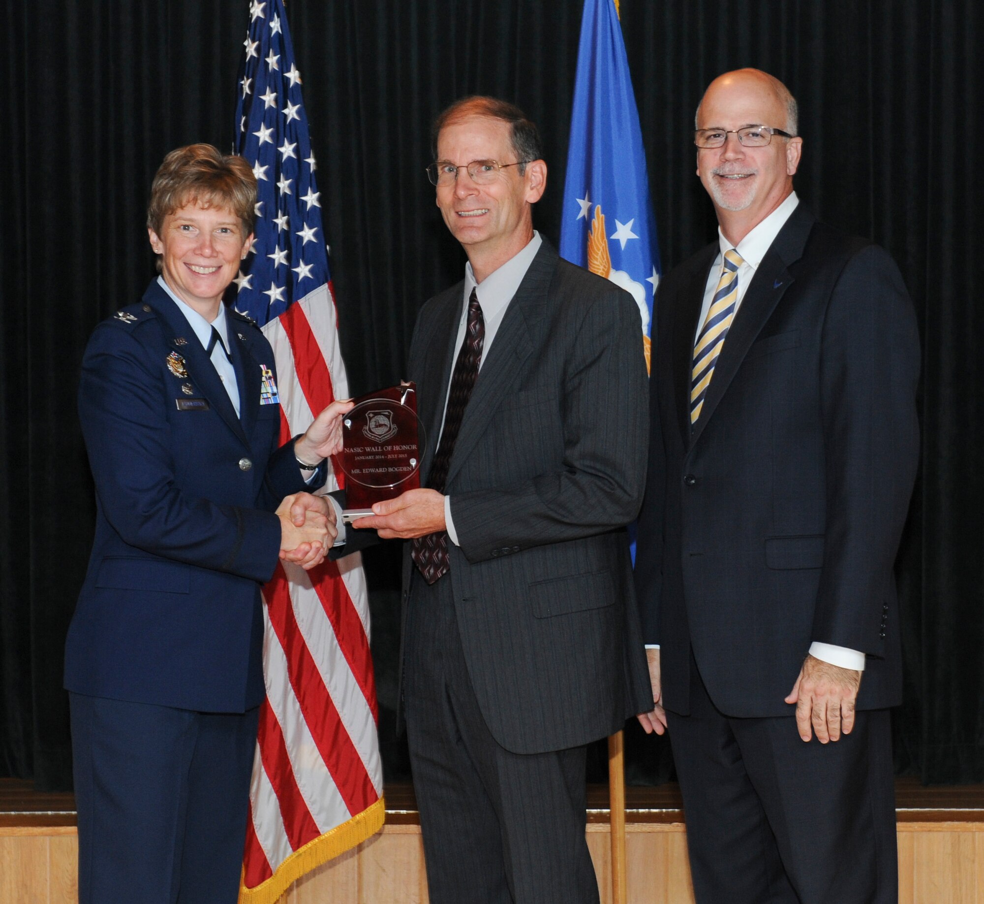 WRIGHT-PATTERSON AIR FORCE BASE, Ohio – Edward Bogden, retired National Air and Space Intelligence Center  employee receives the NASIC Wall of Honor award from Col. Leah Lauderback, NASIC commander and Curt Rowland, NASIC chief scientist, here Aug. 19, 2015.The Wall of Honor is the greatest honor that NASIC can bestow on one of its alumni, It recognizes their significant achievements and is a reflection of their lasting, positive contributions to the center. (U.S. Air Force Photo by Airman 1st Class Samuel Earick)   