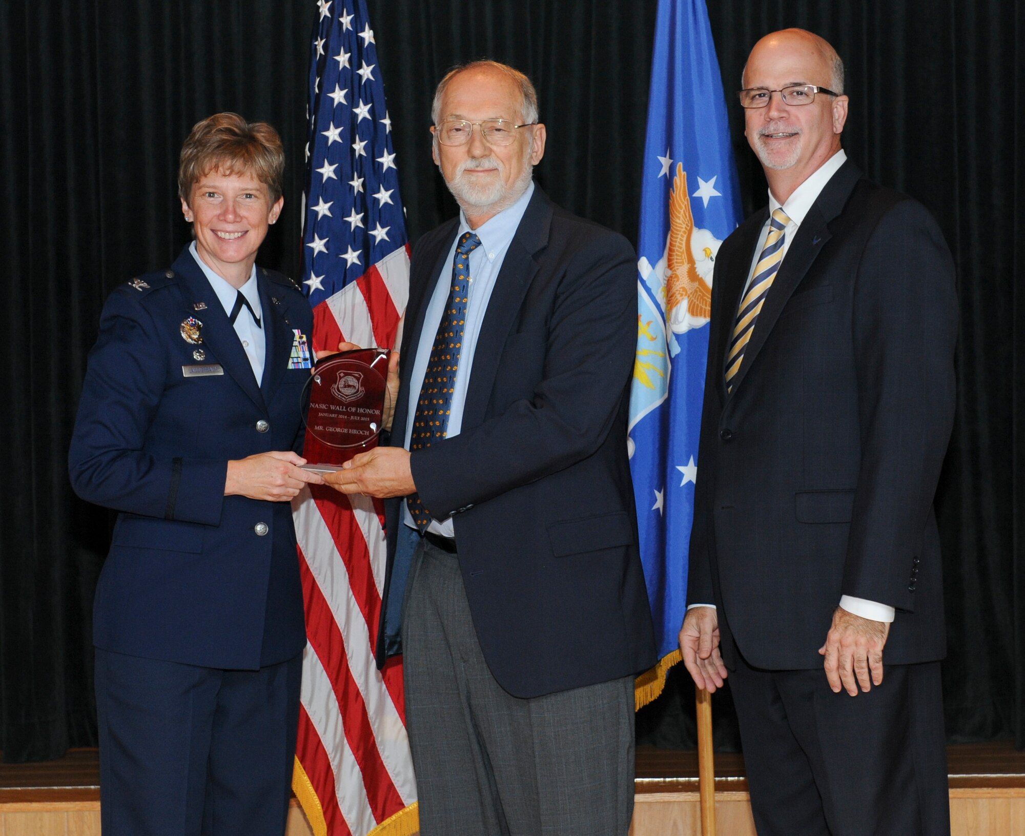 WRIGHT-PATTERSON AIR FORCE BASE, Ohio – Mr. George Hroch, retired National Air and Space Intelligence Center employee, receives the NASIC Wall of Honor award from Col. Leah Lauderback, NASIC commander and Curt Rowland, NASIC chief scientist, here Aug. 19, 2015.The Wall of Honor is the greatest honor that NASIC can bestow on one of its alumni, It recognizes their significant achievements and is a reflection of their lasting, positive contributions to the center. (U.S. Air Force Photo by Airman 1st Class Samuel Earick)  