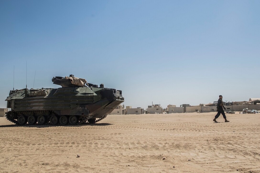 KUWAIT (Aug. 22, 2015) U.S. Marine Lance Cpl. John Figueroa guides Lance Cpl. Giovanni Carrera as he drives an Amphibious Assault Vehicle (AAV-7). Figueroa and Carrera are crewmen with Kilo Company, Battalion Landing Team 3rd Battalion, 1st Marine Regiment, 15th Marine Expeditionary Unit (MEU). These Marines maintain the AAVs to ensure they remain in good condition and are operable in extreme environments. Elements of the 15th MEU are ashore in Kuwait for sustainment training to maintain and enhance the skills they developed during their pre-deployment training period.  The 15th MEU is embarked on the Essex Amphibious Ready Group and deployed to maintain regional security in the U.S. 5th Fleet area of operations. (U.S. Marine Corps photo by Sgt. Emmanuel Ramos/Released)