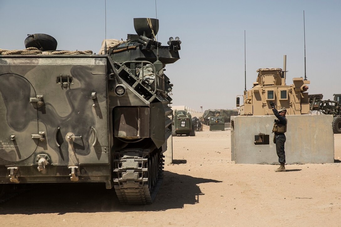 KUWAIT (Aug. 22, 2015) U.S. Marine Cpl. Jeffery Quam guides Lance Cpl. Jose Martinez as he drives an Amphibious Assault Vehicle (AAV-7). Quam is a crew chief and Martinez is crewman with Kilo Company, Battalion Landing Team 3rd Battalion, 1st Marine Regiment, 15th Marine Expeditionary Unit (MEU). These Marines maintain the AAVs to ensure they remain in good condition and are operable in extreme environments. Elements of the 15th MEU are ashore in Kuwait for sustainment training to maintain and enhance the skills they developed during their pre-deployment training period.  The 15th MEU is embarked on the Essex Amphibious Ready Group and deployed to maintain regional security in the U.S. 5th Fleet area of operations. (U.S. Marine Corps photo by Sgt. Emmanuel Ramos/Released)