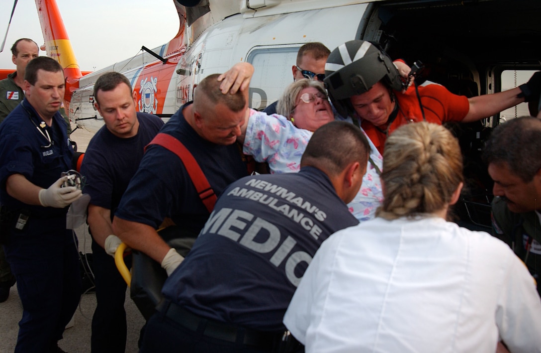 Coast Guard helicopter rescue crew and paramedics from the Mobile area assist a woman onto a gurney at the Coast Guard base in Mobile, Ala., Sept. 1, 2005. U.S. Coast Guard photograph by Petty Officer 2nd Class NyxoLyno Cangemi